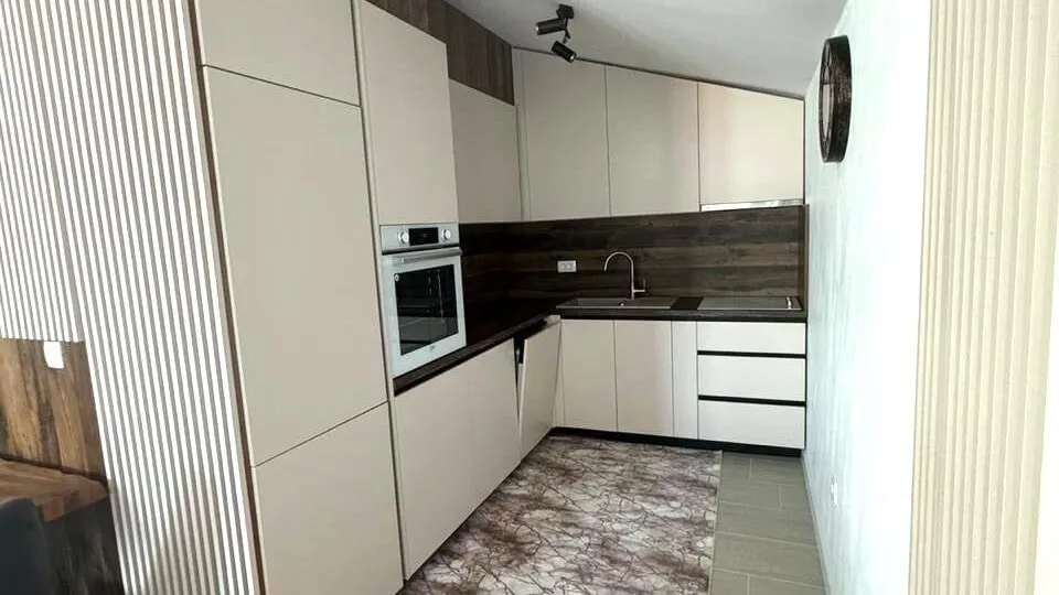 Moderne Küche in einer Wohnung in Tivat, Montenegro: helle Fronten, Einbaugeräte und Holzoptik.