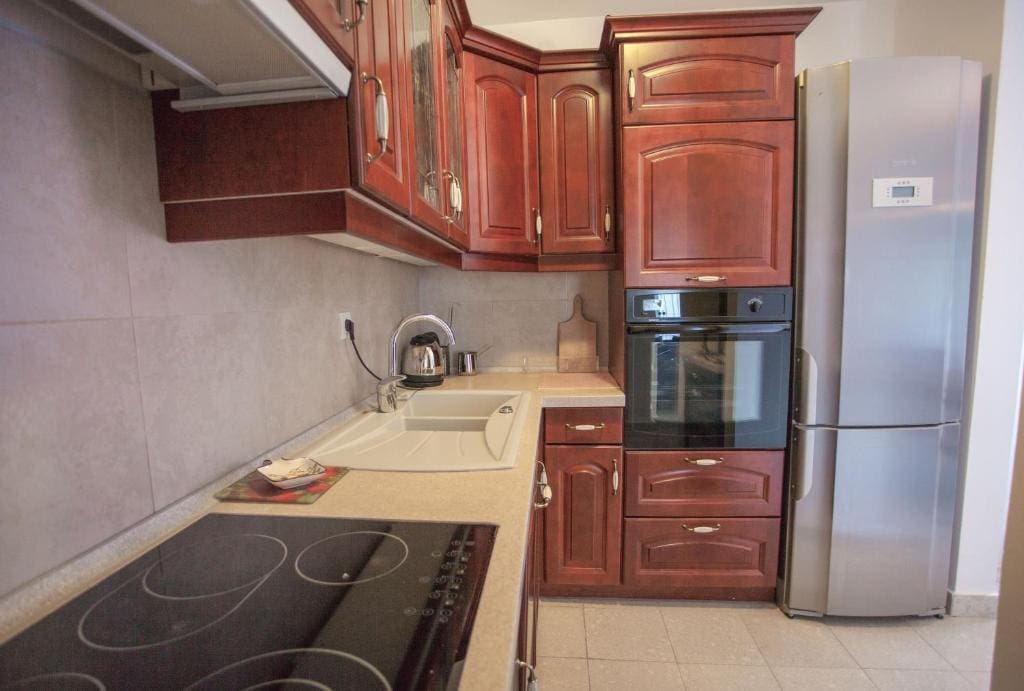 Küche in einer Wohnung in Budva, Montenegro: klassische Einbauküche aus dunklem Holz, mit Einbaugeräten und Herd.
