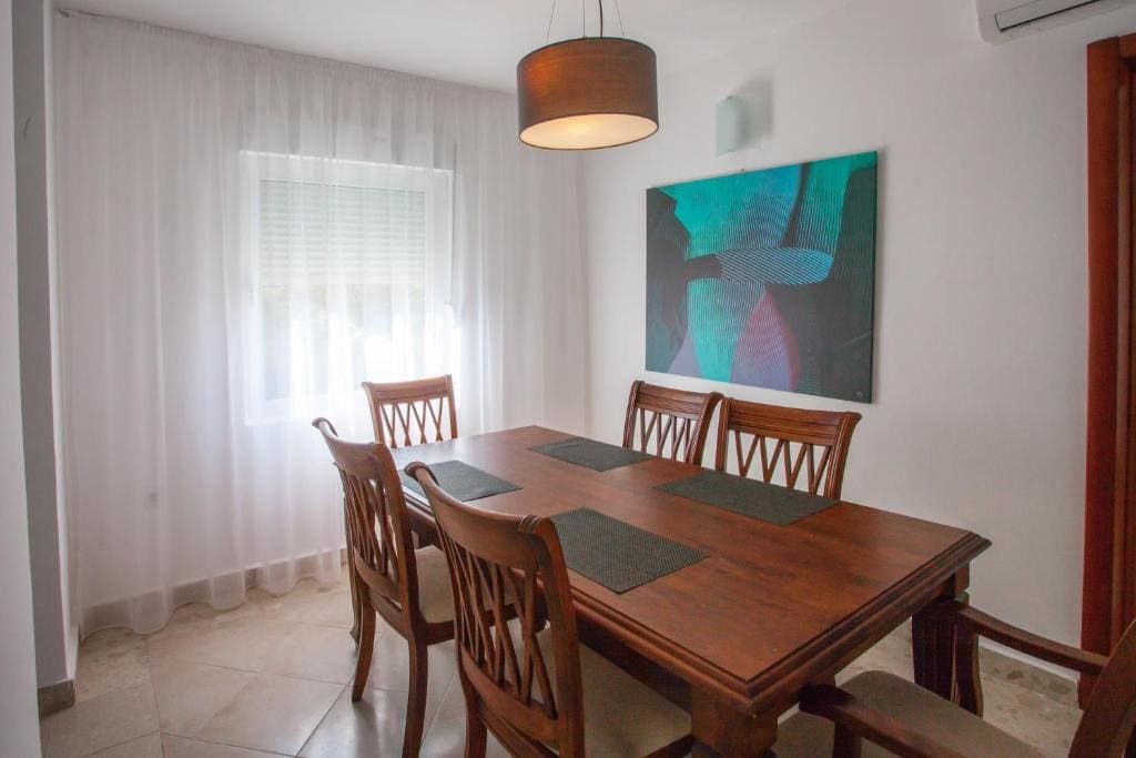 Essbereich in einer Wohnung in Budva, Montenegro: Holztisch mit Stühlen, modernes Gemälde und helles Interieur.