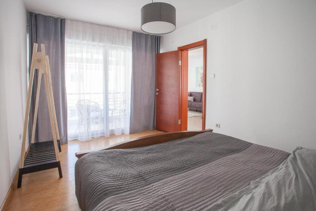 Helles Schlafzimmer mit Doppelbett und Zugang zum Balkon in einer Wohnung, Budva, Montenegro. Modernes Interieur.