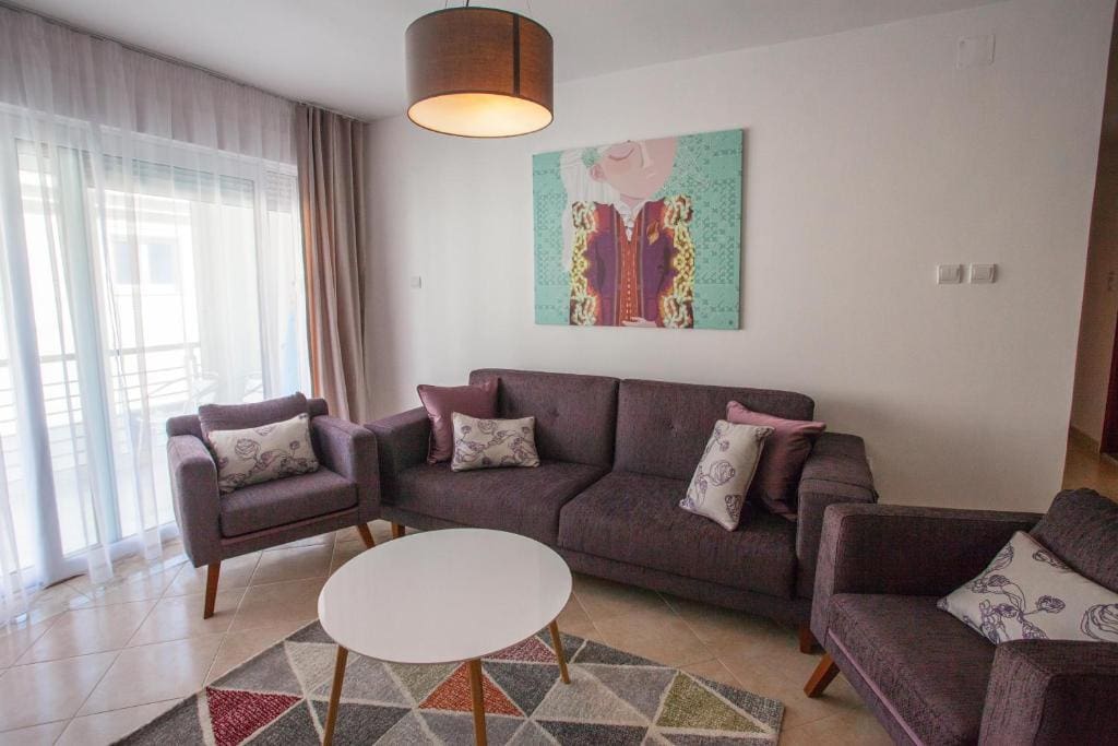 Gemütliches Wohnzimmer mit Polstermöbeln und Zugang zum Balkon in einer Wohnung in Budva, Montenegro. Modernes Interieur.