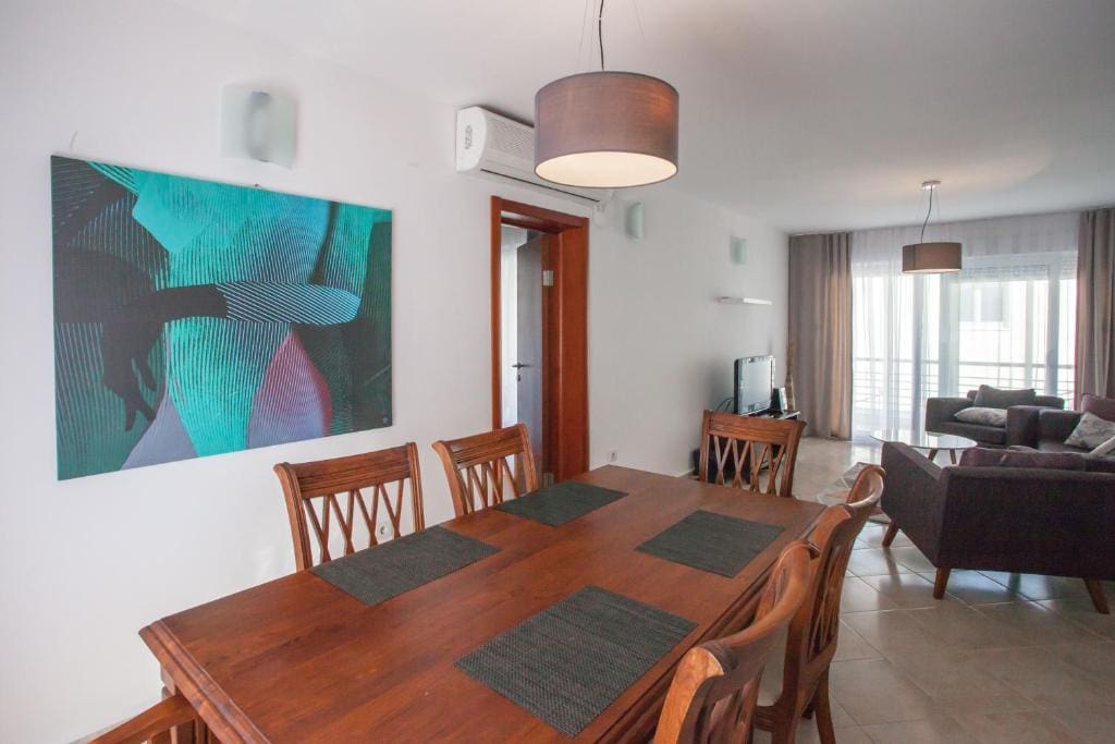 Innenansicht des Wohnzimmers mit Essbereich in einer Wohnung in Budva, Montenegro: Holztisch, Polstermöbel und Panoramafenster.