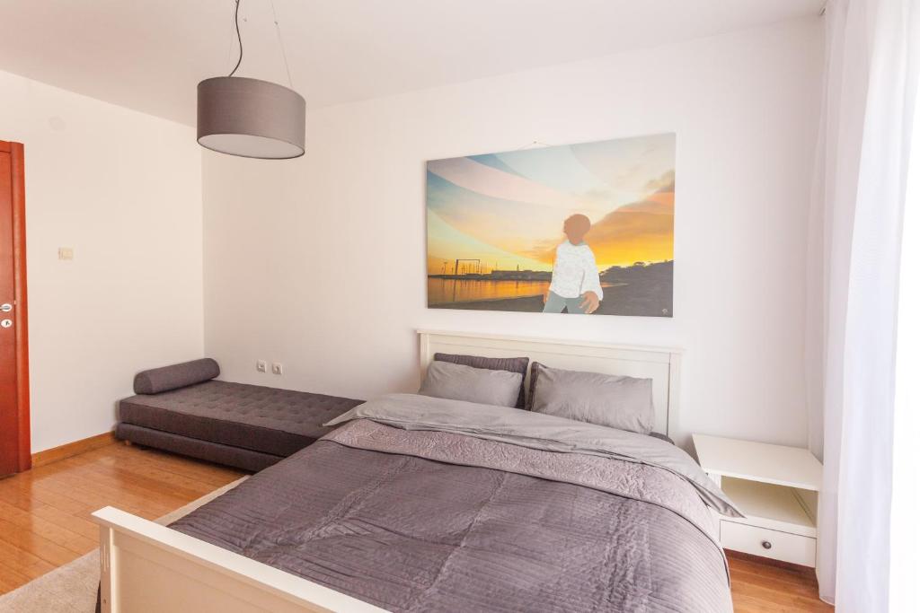 Helles Schlafzimmer mit Doppelbett und Sofa in einer Wohnung in Budva, Montenegro, modernes Interieur mit einem Gemälde.