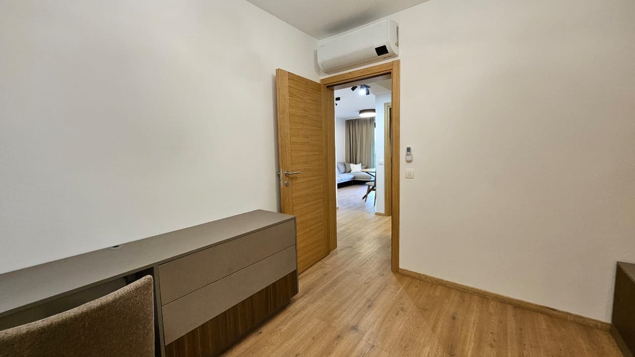 Modernes Schlafzimmer mit Kommode und Klimaanlage in einer zum Verkauf stehenden Wohnung, Budva, Montenegro. Blick ins Wohnzimmer durch die Tür.