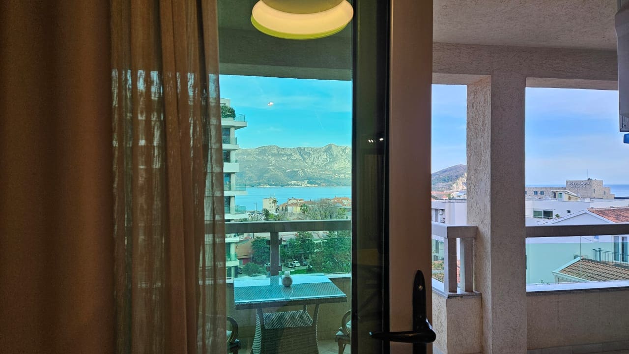 Blick vom Balkon der Wohnung in Budva, Montenegro: Rattanmöbel, Panoramablick auf Meer und Berge, moderne Ausstattung.