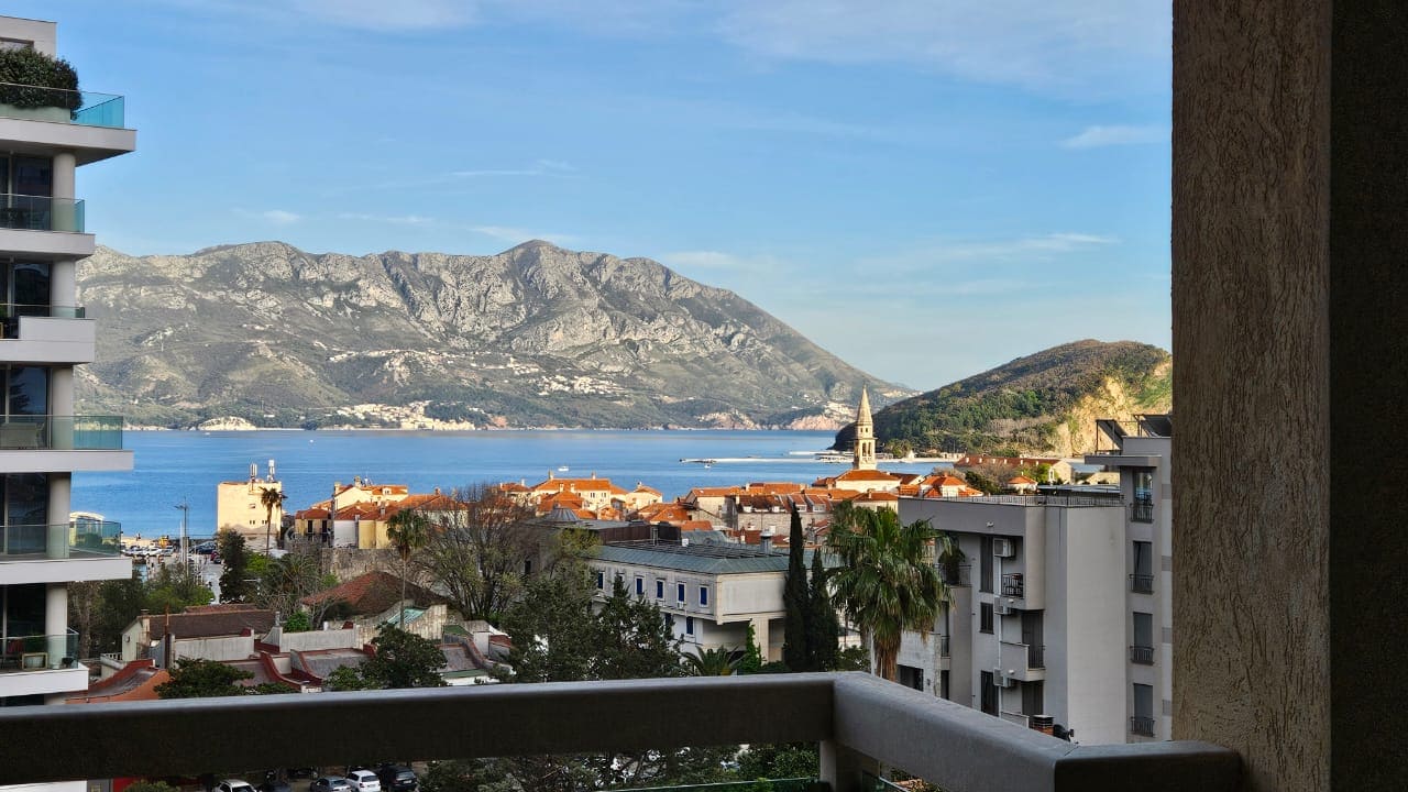 Blick vom Balkon der Wohnung in Budva, Montenegro: Panorama auf die Adria, Berge und die Altstadt mit Ziegeldächern.