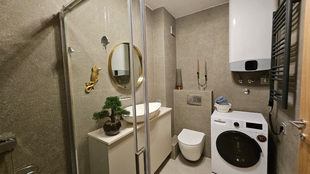 Modernes Badezimmer in einer Wohnung in Budva, Montenegro: Duschkabine, Waschmaschine und stilvolle Ausstattung.