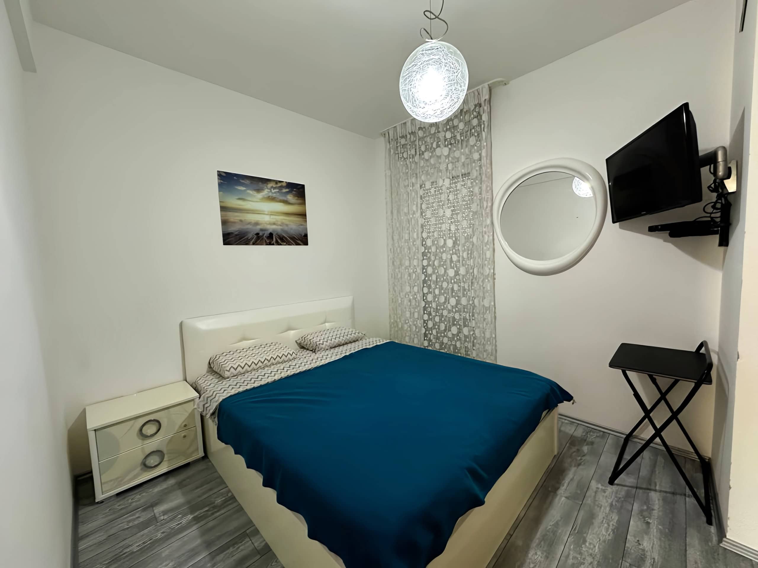 Gemütliches Schlafzimmer mit Doppelbett in einer Wohnung in Bečići, Montenegro: helles Interieur, TV und stilvolle Ausstattung.