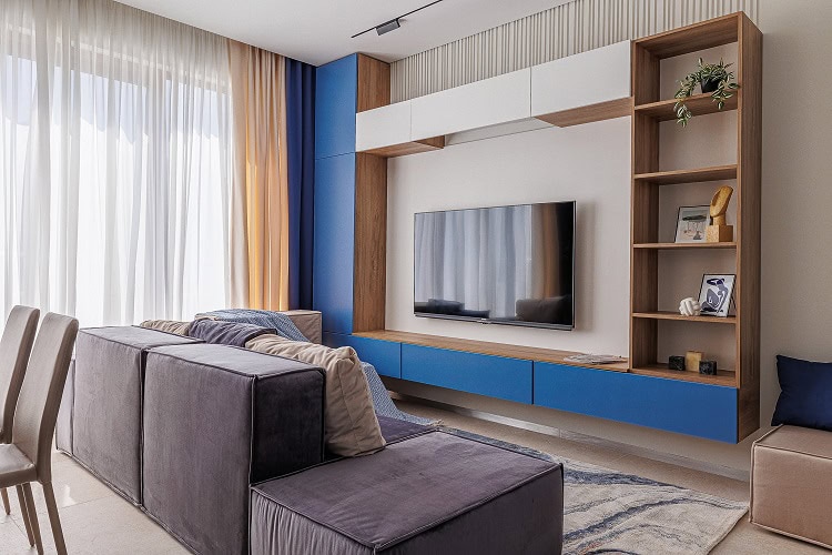 Moderna dnevna soba u stanu u Bečićima, Crna Gora: modularna garnitura, TV zona sa plavim frontovima i panoramski prozori.