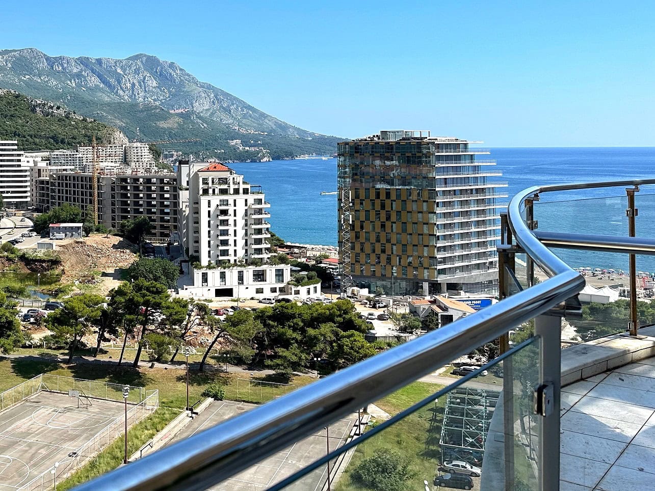 Pogled sa balkona apartmana u Bečićima, Crna Gora: panorama mora, planina i modernih stambenih kompleksa letovališta.