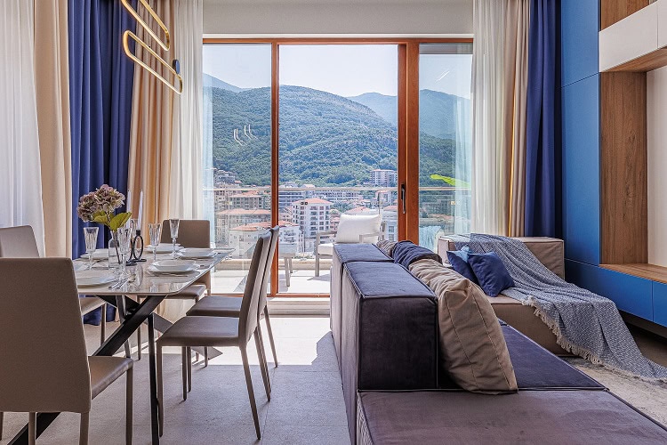 Dnevni boravak sa panoramskim pogledom na planine u stanu u Bečićima, Crna Gora: moderan nameštaj i trpezarija.