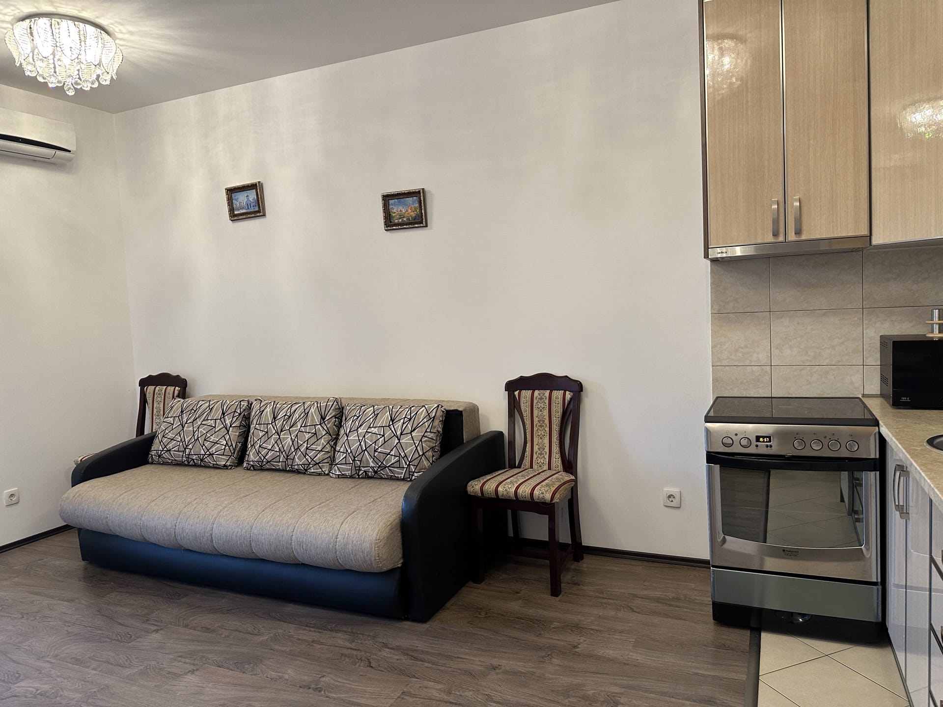Wohnzimmer mit Küche in einer Wohnung in Budva, Montenegro: Sofa, Essstühle, Küchenzeile und Herd.