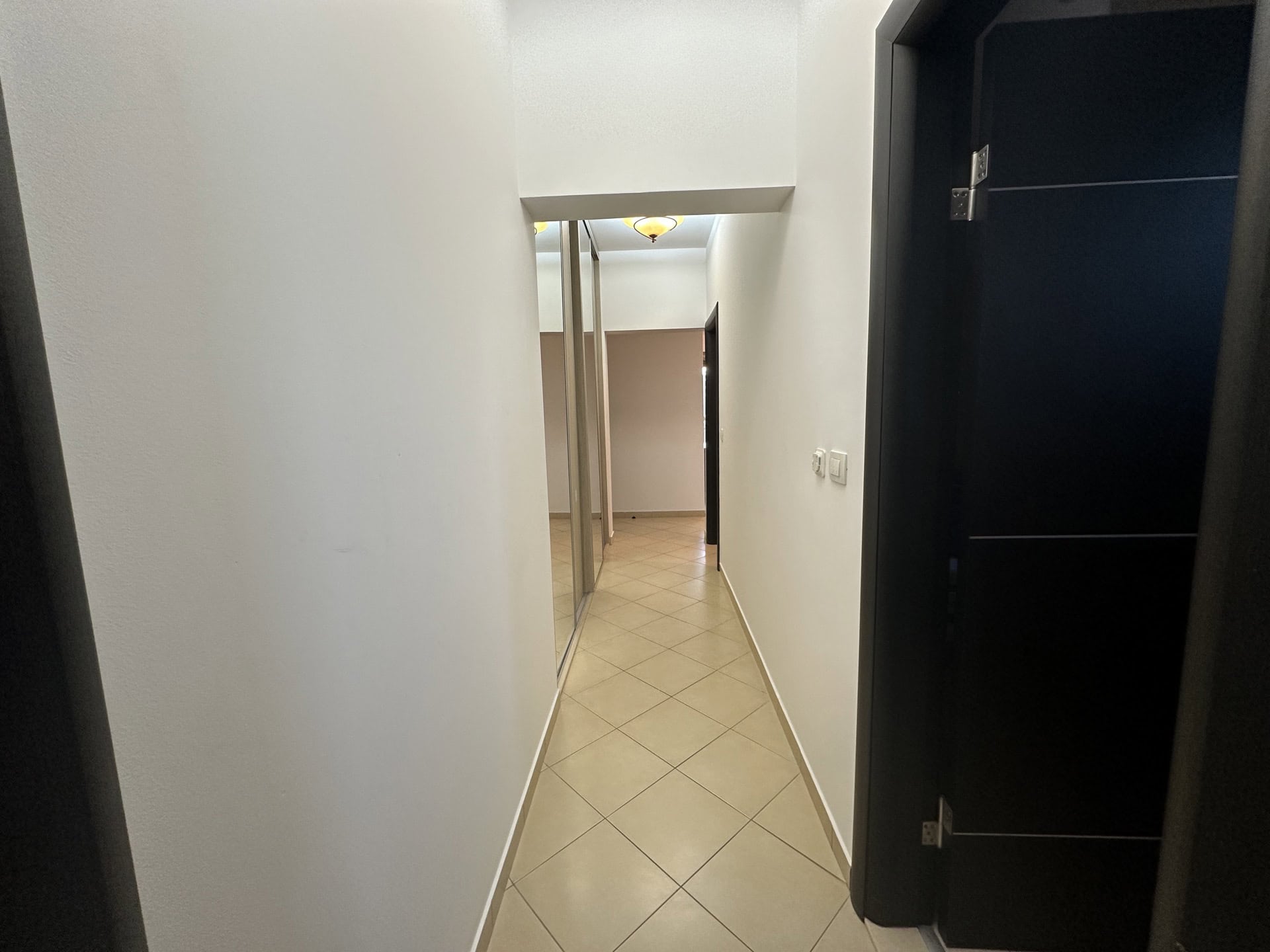 Heller Flur in einer Wohnung in Budva, Montenegro: Fliesenboden, Einbauschrank mit Spiegeltüren und Innentüren.