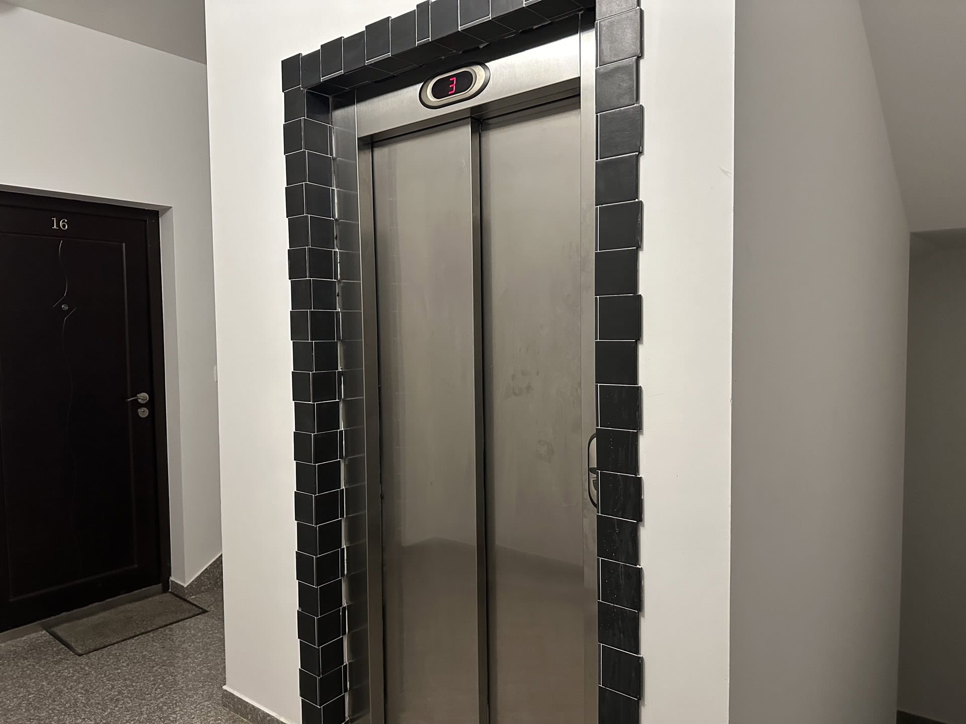 Moderner Aufzug mit schwarzer Fliesenverkleidung im Treppenhaus eines Wohnhauses in Budva, Montenegro.