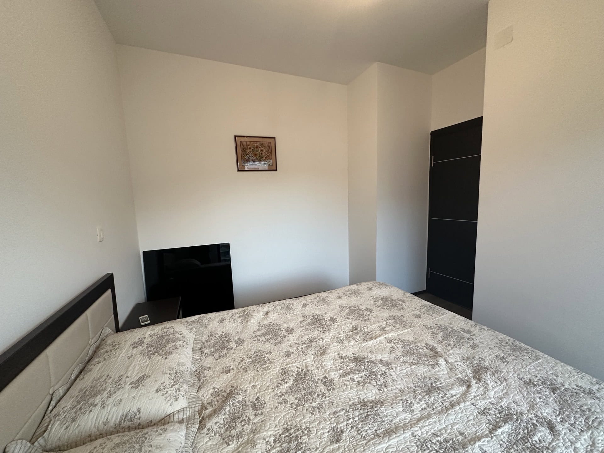 Helles Schlafzimmer mit Doppelbett in einer Wohnung in Budva, Montenegro: moderne Ausstattung und dunkle Innentür.