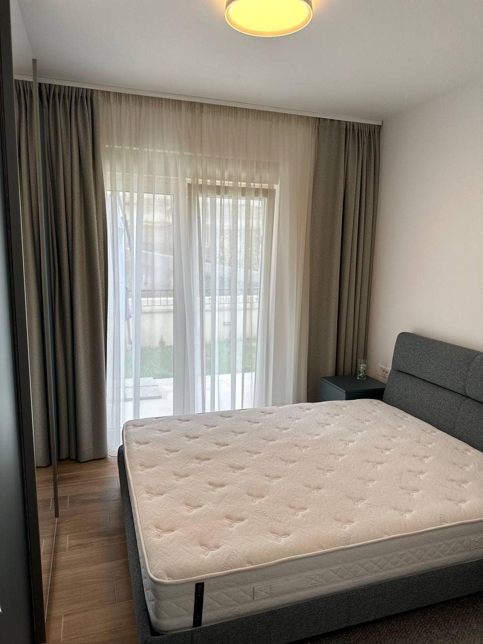 Savremena spavaća soba sa bračnim krevetom i panoramskim prozorom u stanu, grad Tivat, Crna Gora.