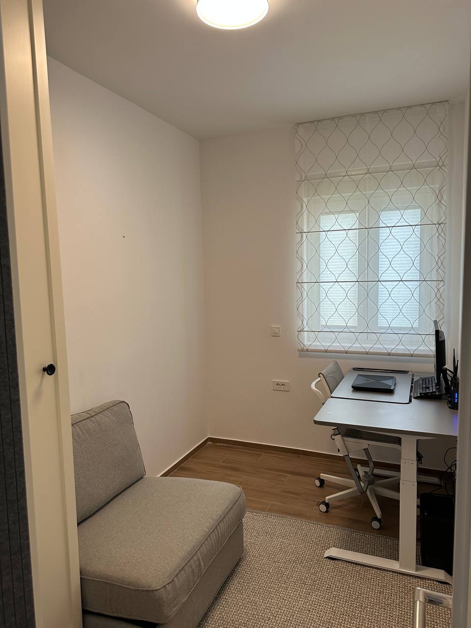 Mala radna soba sa radnim stolom i foteljom u stanu u Tivtu, Crna Gora, svetla završna obrada i laminat.