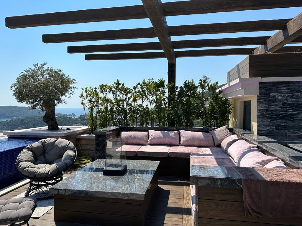 Penthouse-Terrasse in Bečići, Montenegro: Entspannungsbereich mit Sofa, Pool und Meerblick.