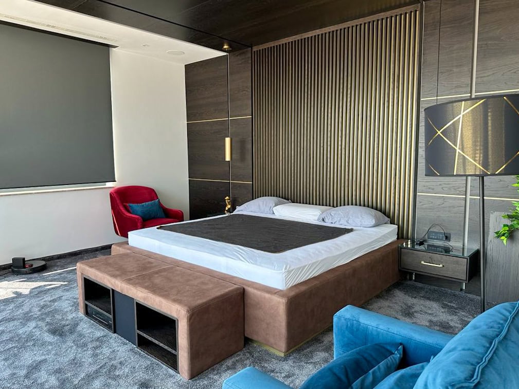 Designer-Schlafzimmer im Penthouse, Bečići, Montenegro: Doppelbett, Wandverkleidung mit Lamellen und Polstermöbel.