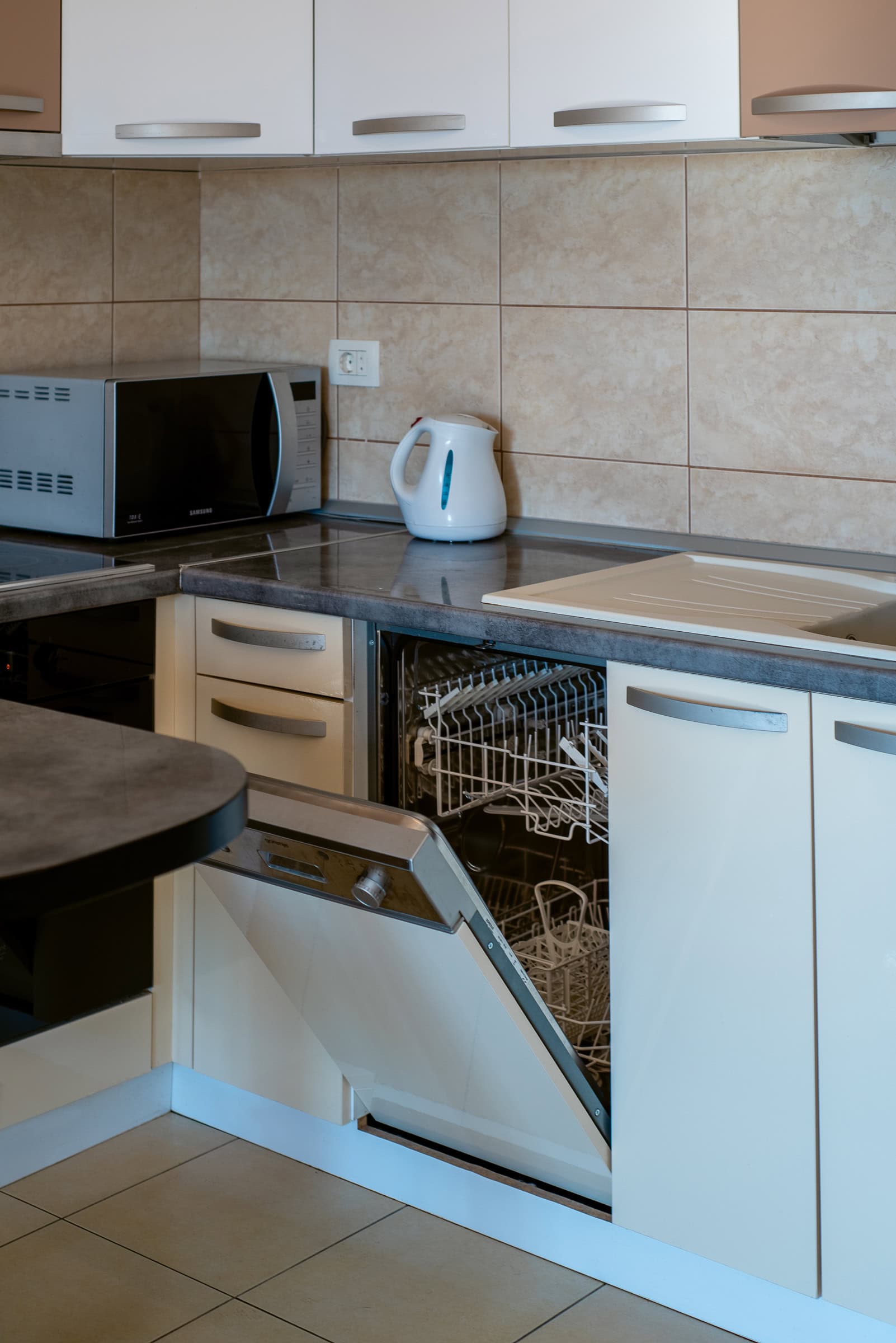 Moderne Küche in einer Wohnung in Budva, Montenegro: integrierter Geschirrspüler, helle Fronten und Haushaltsgeräte.