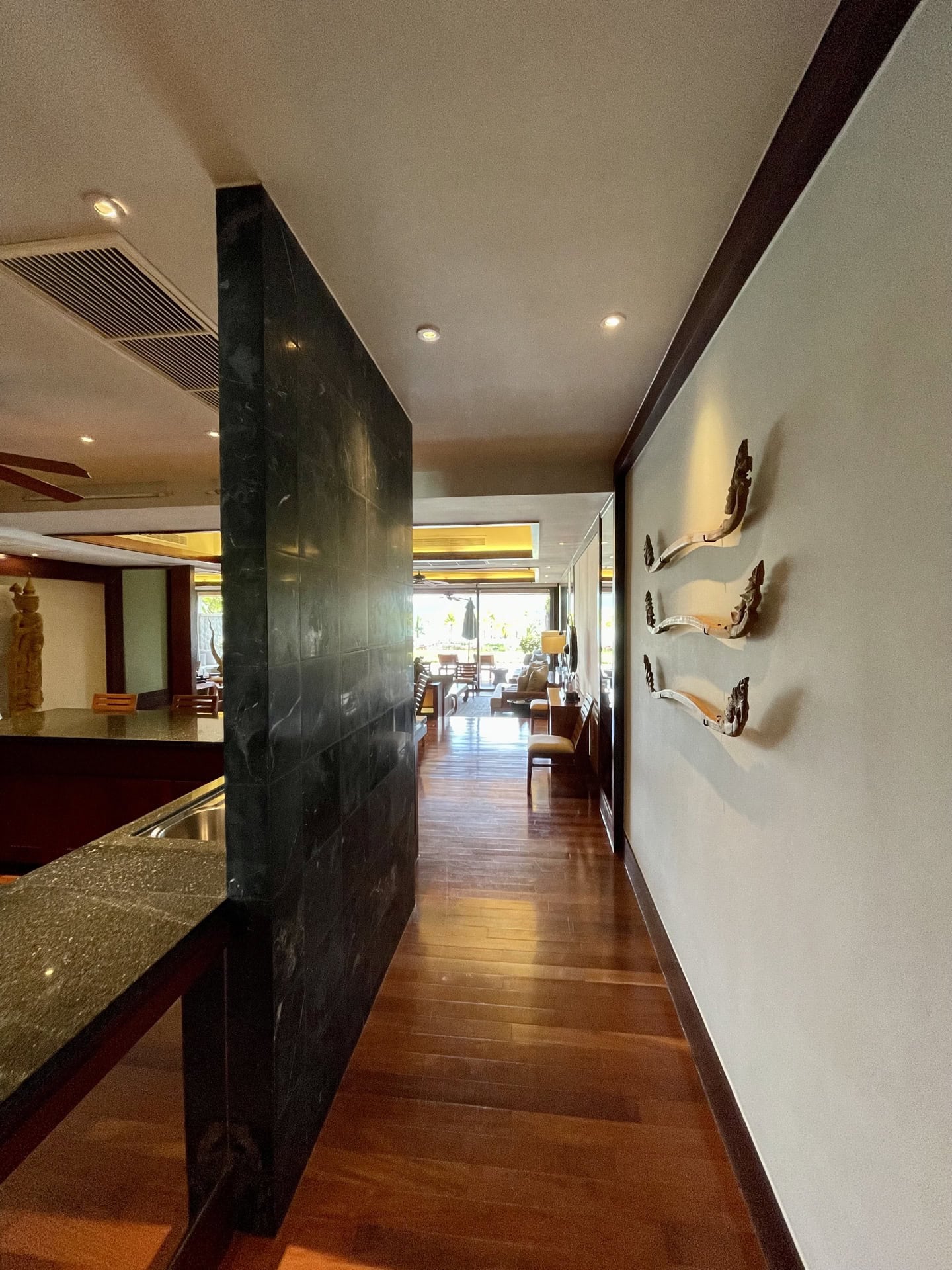 Innenraum des Wohnzimmers mit dunkler Steinwand, Holzboden und Dekor in einer Luxuswohnung in Phuket, Thailand.