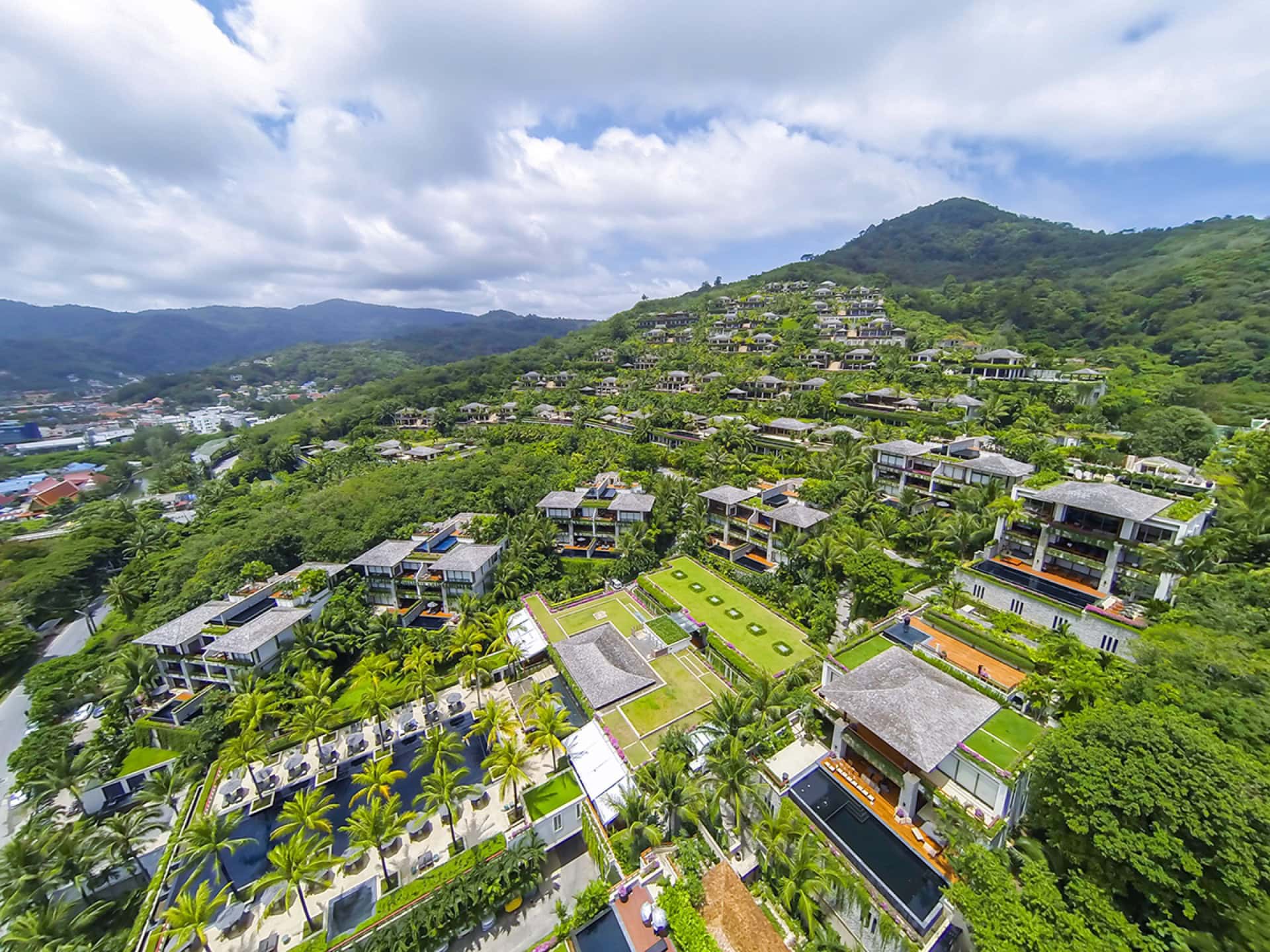 Panoramablick auf eine exklusive Wohnanlage mit Villen und Pools inmitten tropischer Vegetation auf Phuket, Thailand