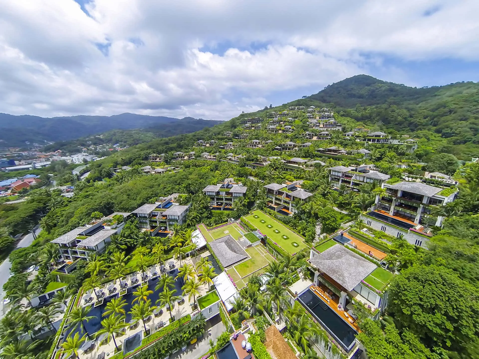Panoramablick auf eine exklusive Wohnanlage mit Villen und Pools inmitten tropischer Vegetation auf Phuket, Thailand