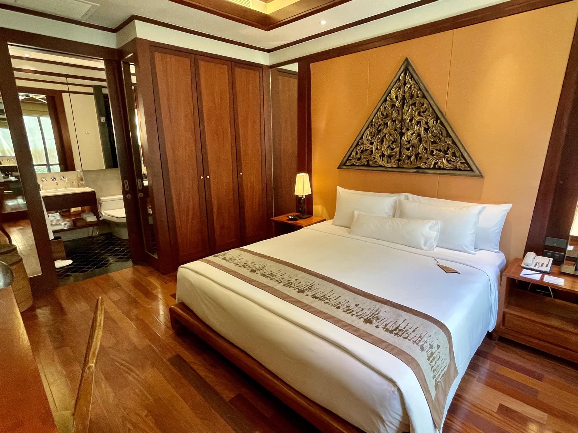 Schlafzimmer in einer Wohnung auf Phuket: Doppelbett, Holzmöbel, Dekor im thailändischen Stil und Badezimmer.