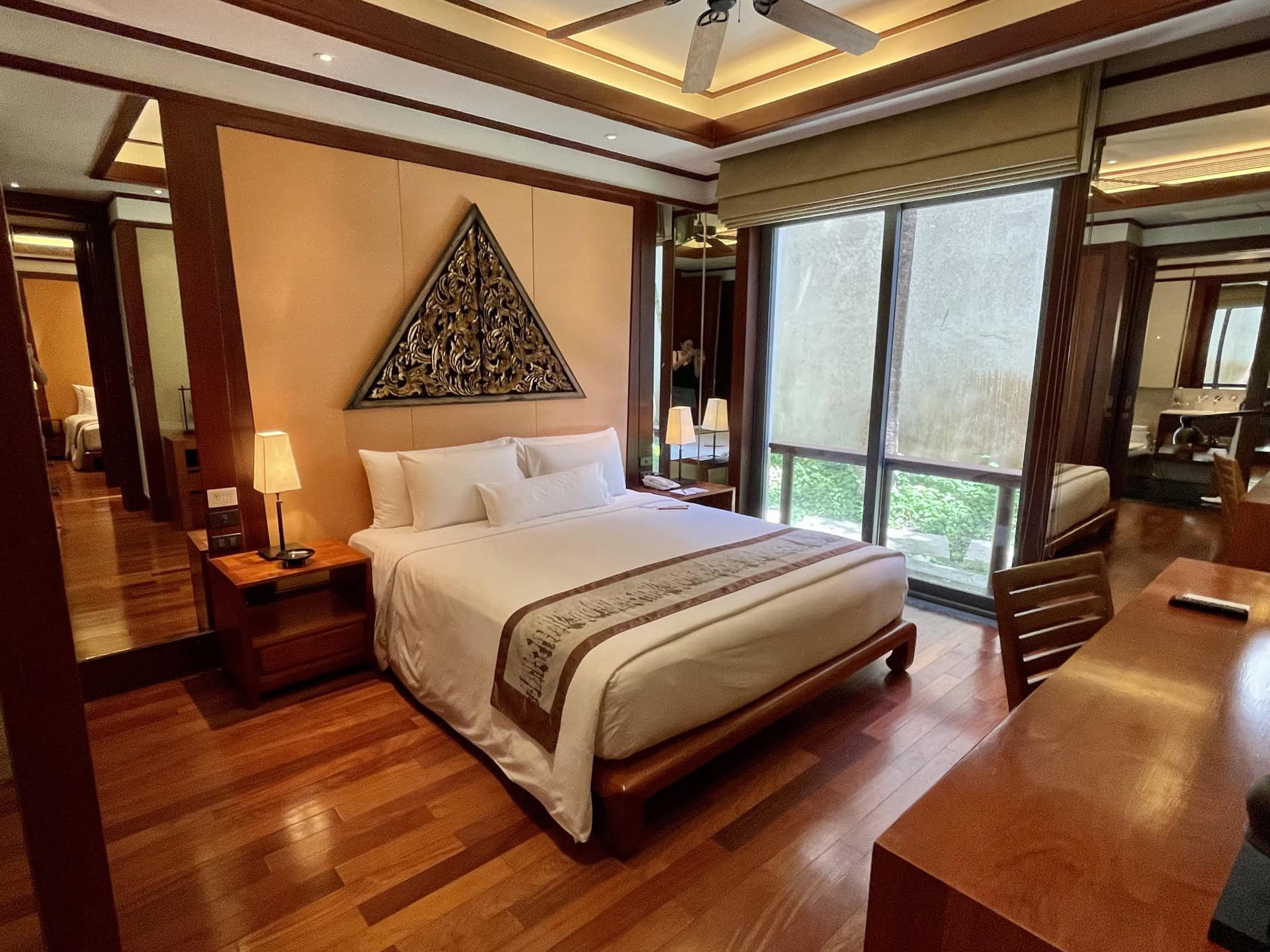 Schlafzimmer in einer Wohnung in Phuket, Thailand: Doppelbett, Holzverkleidung, Dekor und Panoramafenster.