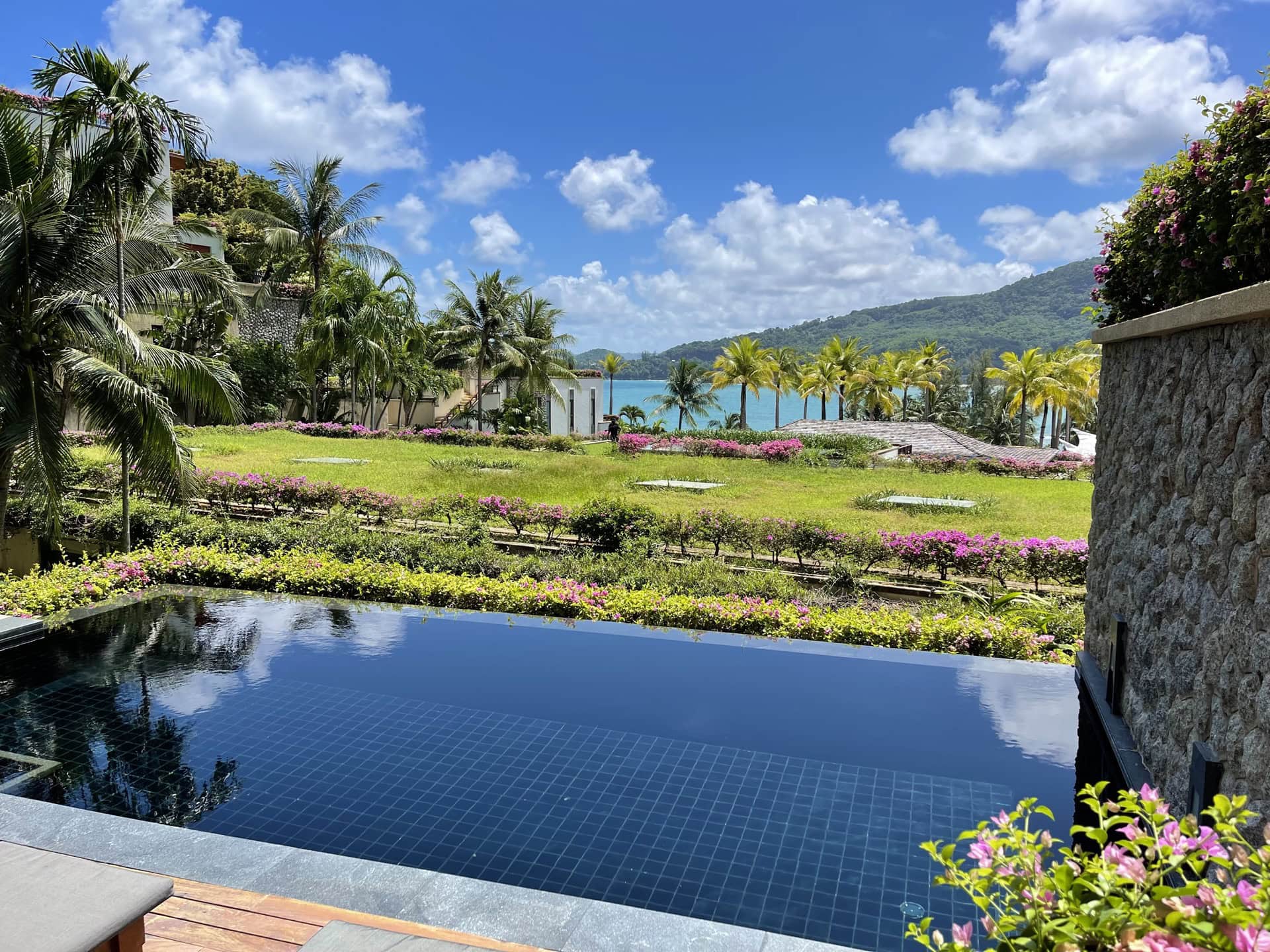 Blick auf den Infinity-Pool, den tropischen Garten und das Meer von den Luxusapartments in Phuket, Thailand.