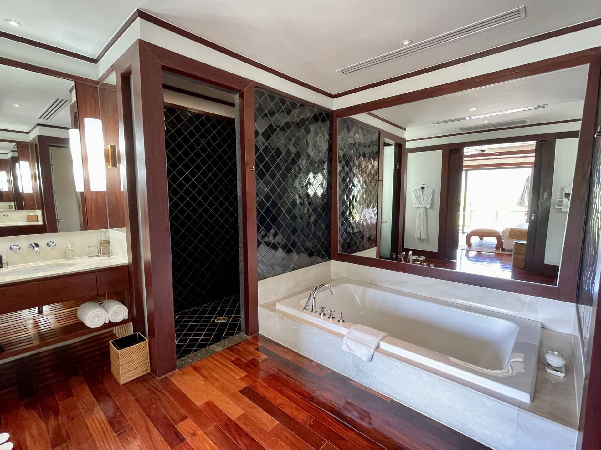 Luxuriöses Badezimmer mit Holzboden, eingebauter Badewanne und Duschkabine in einer Wohnung in Phuket, Thailand
