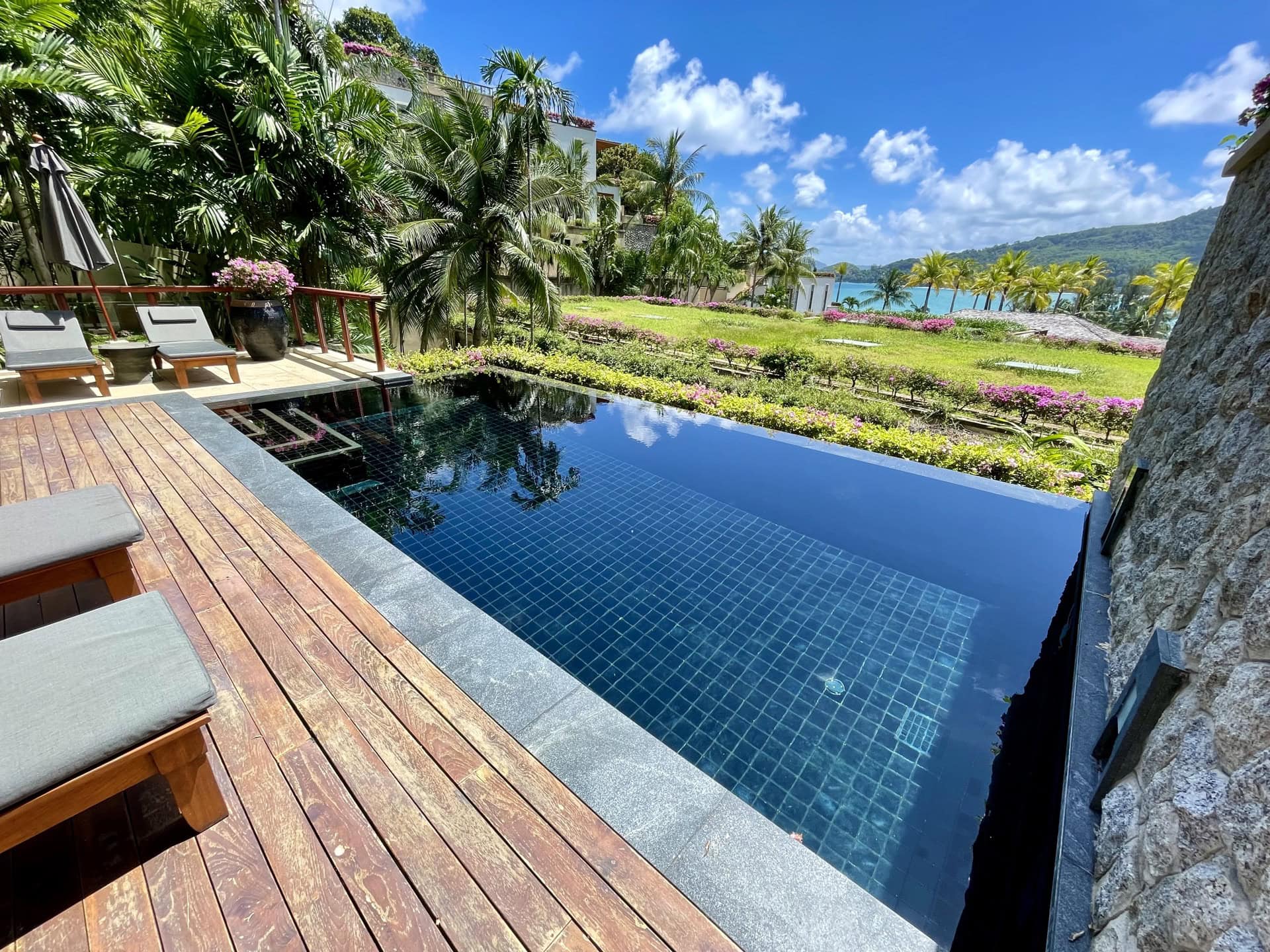 Privater Pool mit Holzterrasse und Liegestühlen in exklusiven Apartments auf Phuket, Thailand, mit Meer- und Gartenblick.
