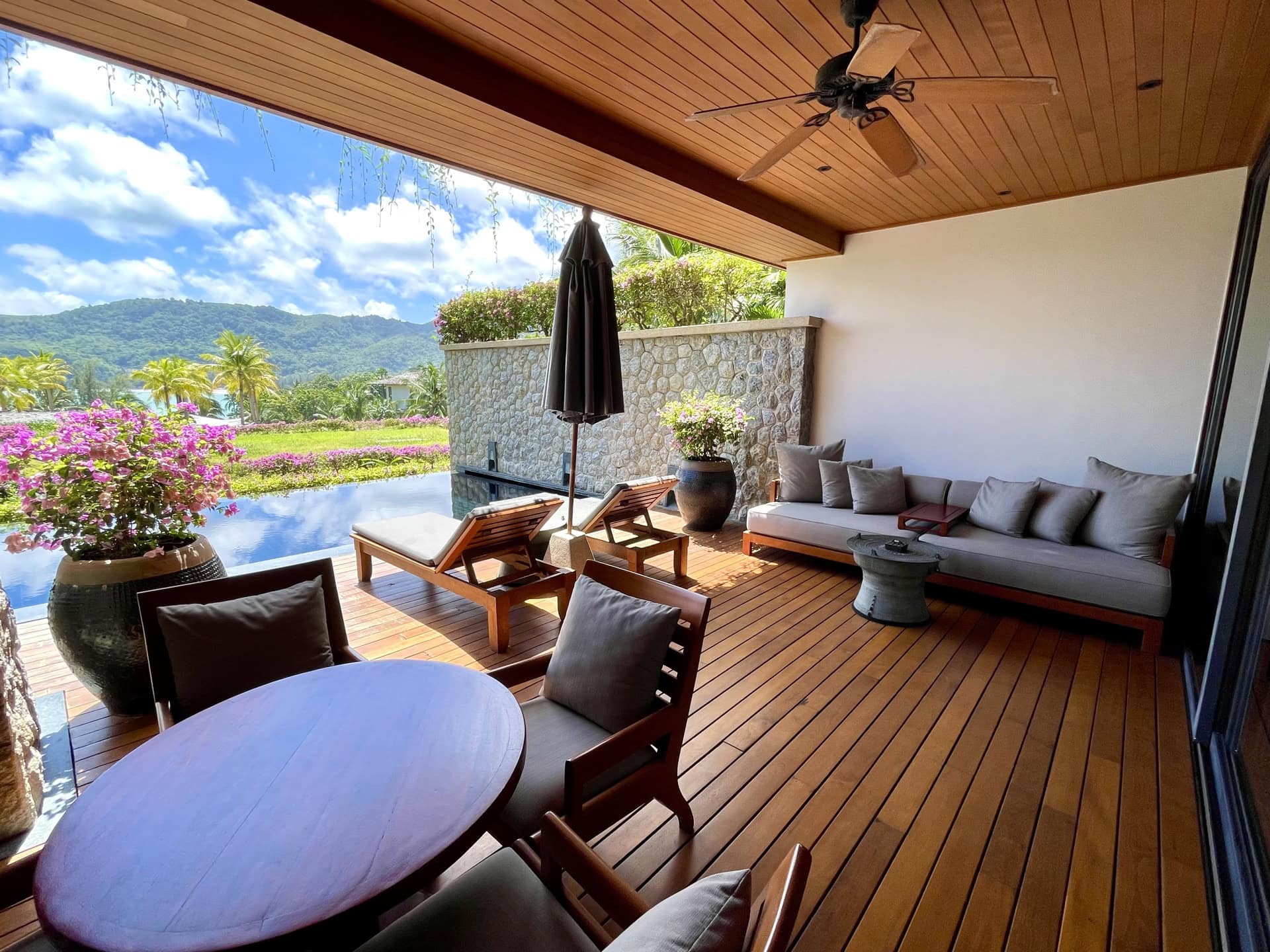 Terrasse der Apartments auf Phuket mit privatem Pool, Holzdeck, Sonnenliegen und Blick auf tropische Berge.