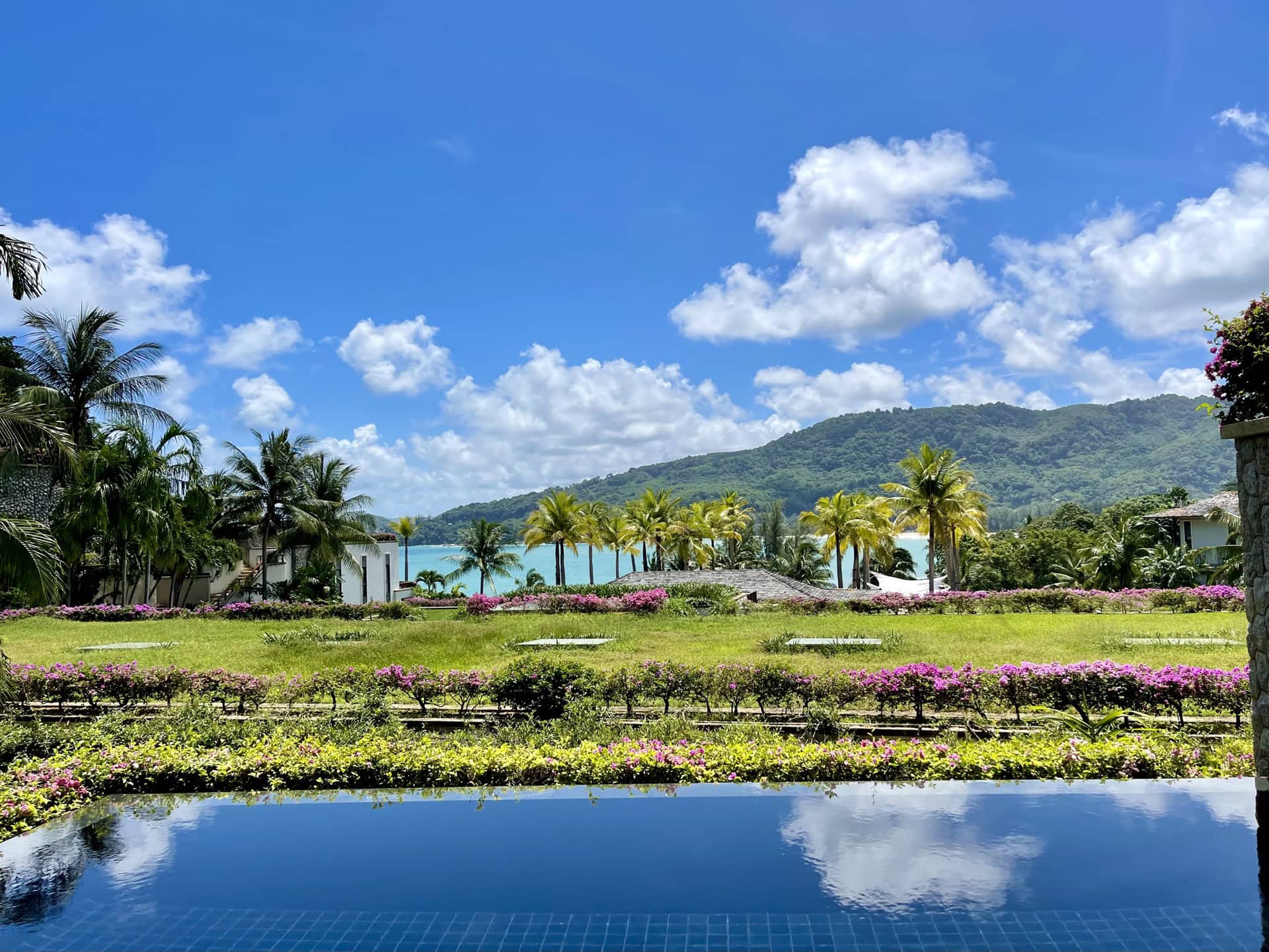 Blick auf den Pool, den tropischen Garten und das Meer von der Terrasse der Wohnung in Phuket, Thailand. Panoramablick mit Palmen.