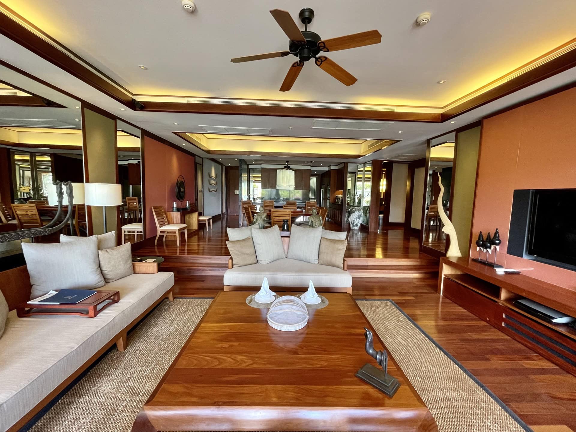 Geräumiges Wohnzimmer in einer Wohnung auf Phuket mit Holzmöbeln, Deckenventilator und stilvollem Interieur.