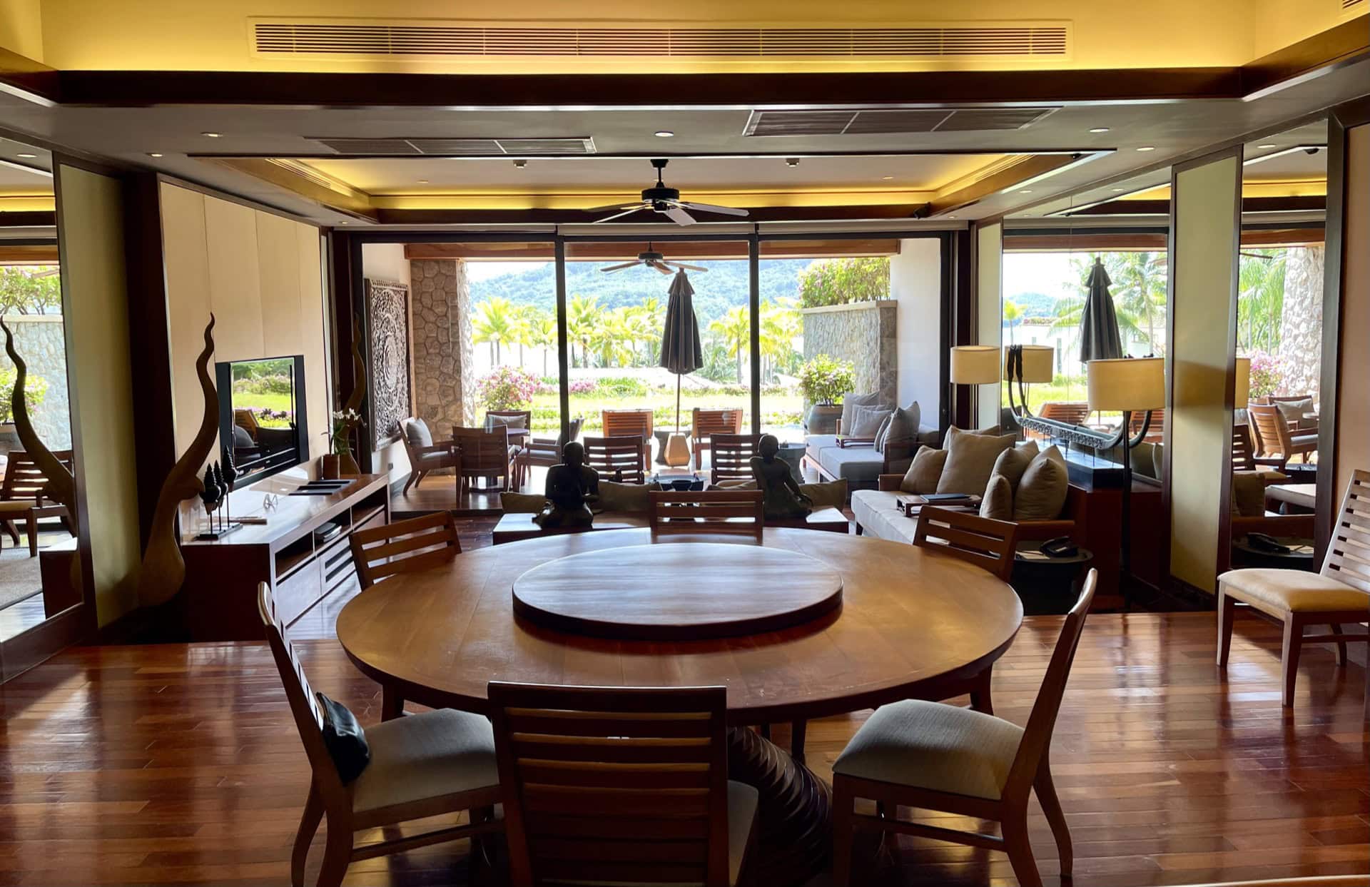 Luxuriöses Wohnzimmer mit Essbereich, Holzmöbeln und Panoramablick auf den tropischen Garten in Phuket, Thailand.