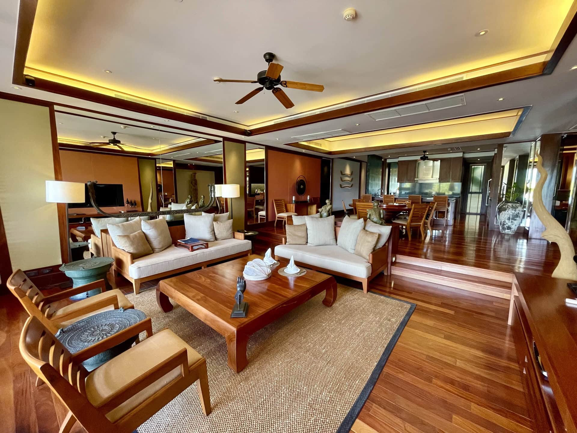 Geräumiges Wohnzimmer mit Holzmöbeln, weichen Sofas und Essbereich in exklusiven Apartments auf Phuket, Thailand