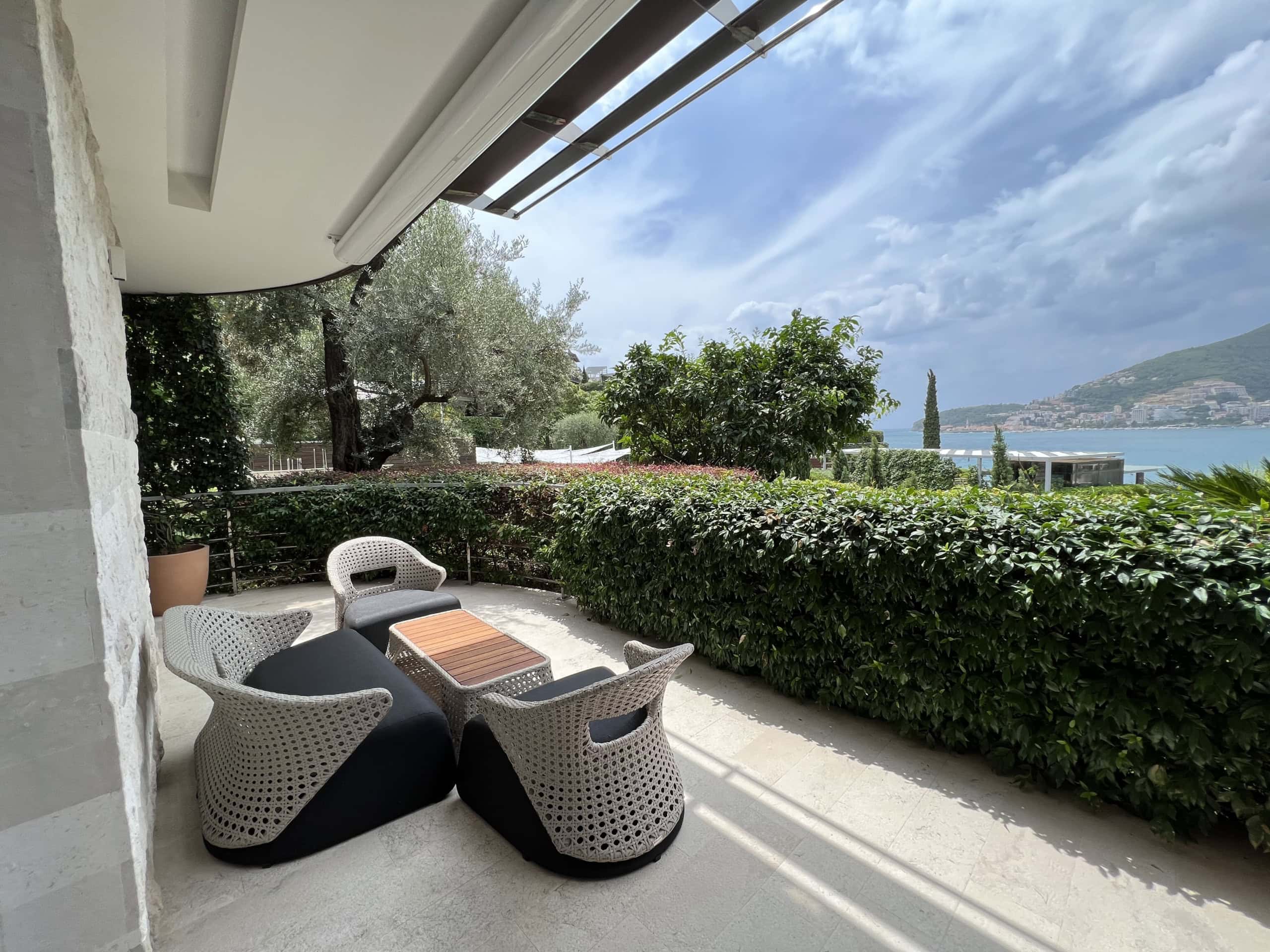 Terrasse mit Rattanmöbeln und Meerblick in einer Wohnanlage in Budva, Montenegro. Gemütliche Sitzecke auf dem Balkon.