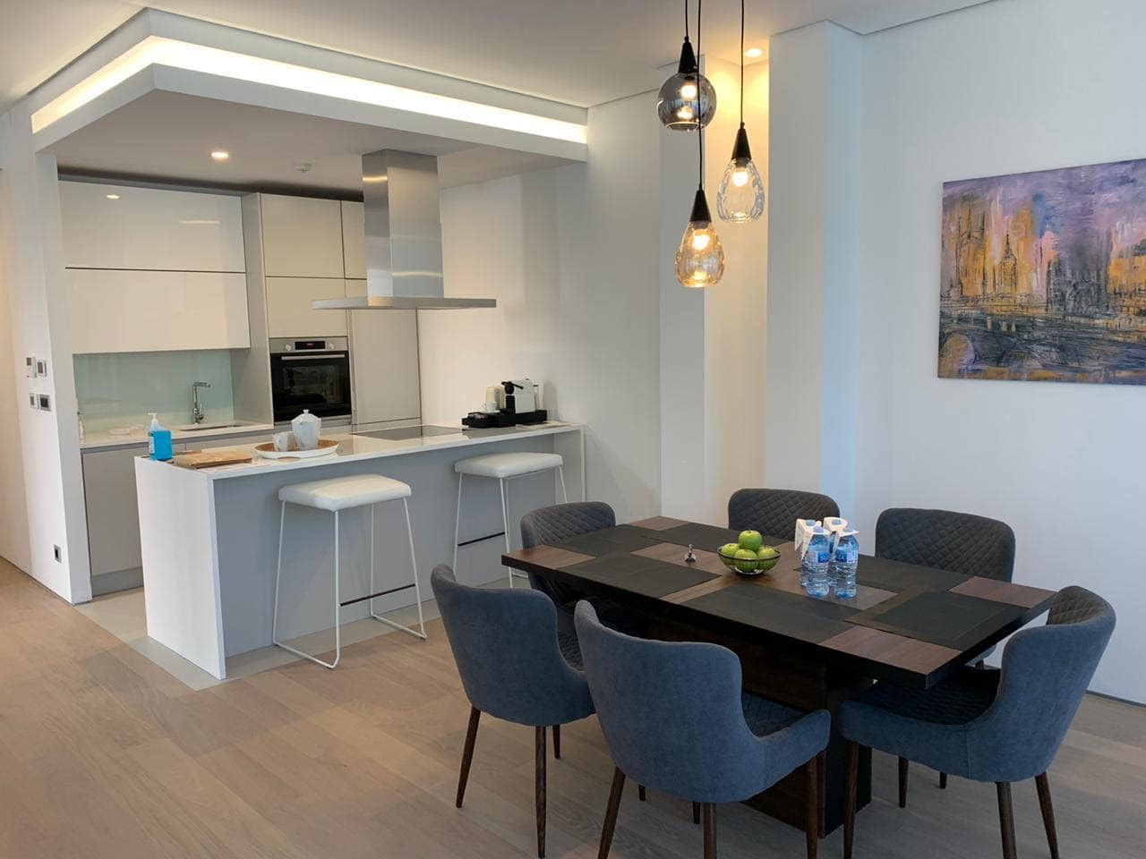 Moderne Wohnküche in ЖК Будva, Montenegro: weiße Möbel, Bartheke, Essbereich mit grauen Stühlen.