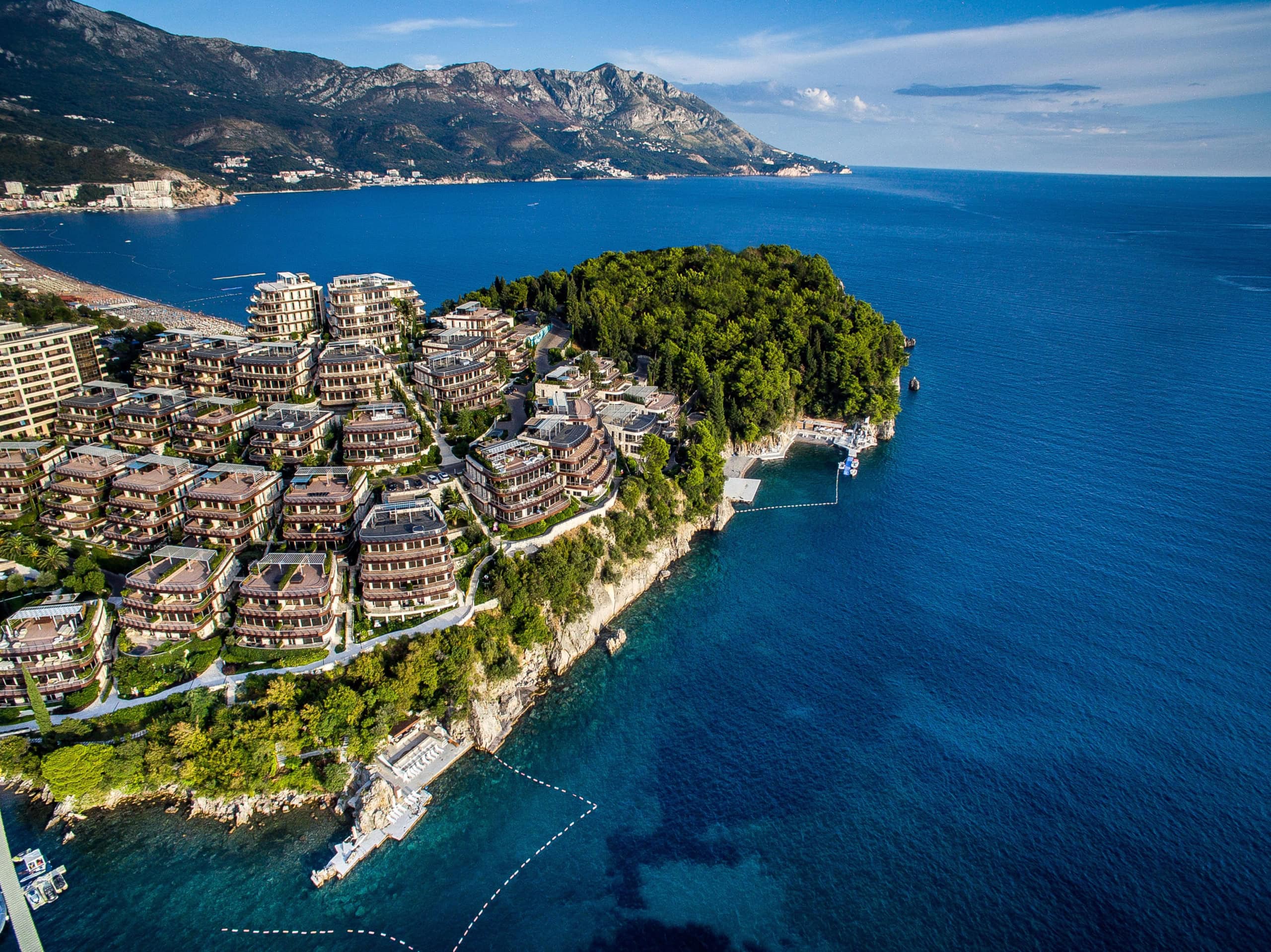 Luftaufnahme des exklusiven Wohnkomplexes Dukley Gardens in Budva, Montenegro, mit Zugang zum Meer und Bergpanorama.