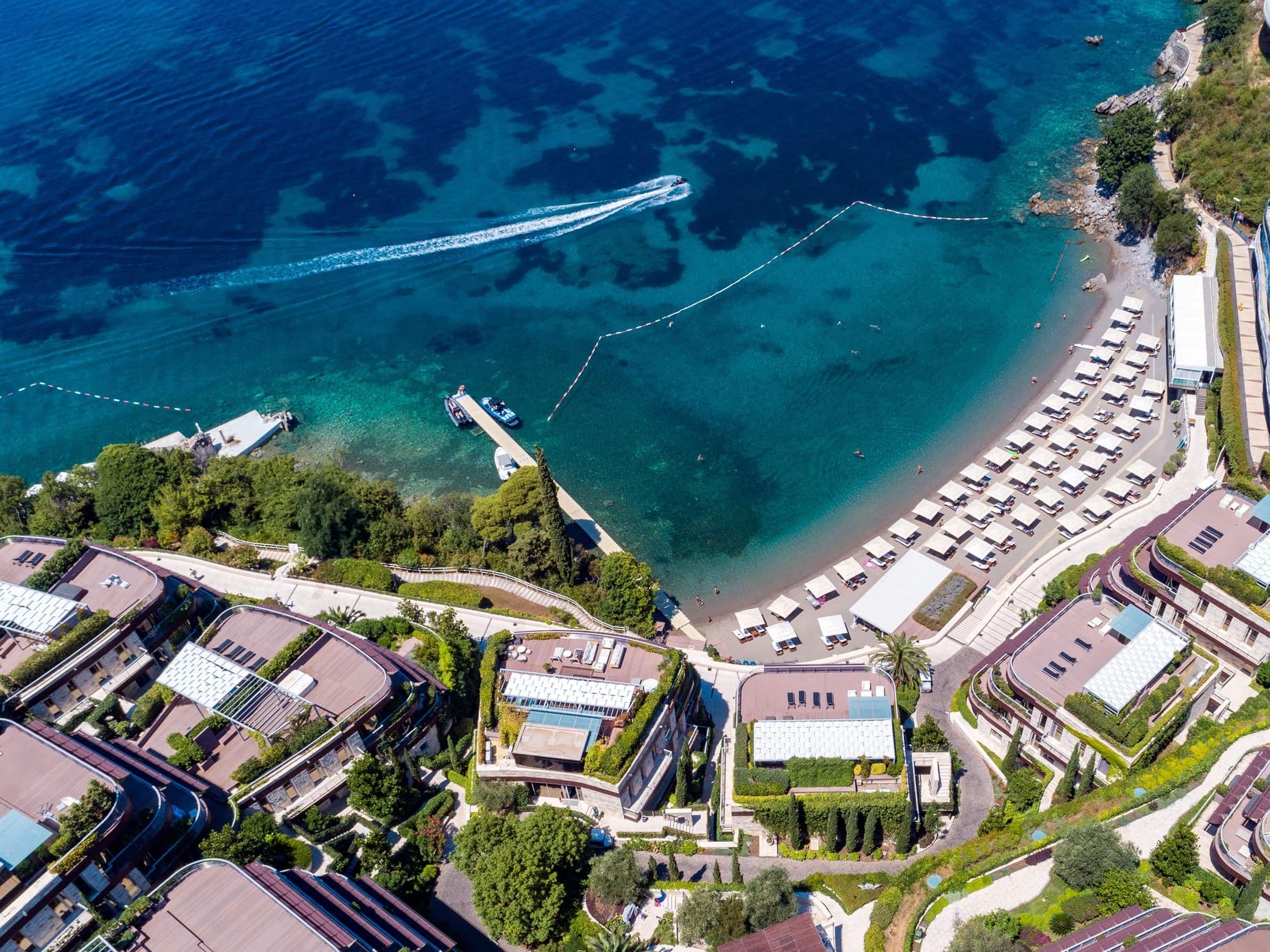 Luftaufnahme eines exklusiven Wohnkomplexes in Budva, Montenegro, mit Privatstrand und Yachthafen.