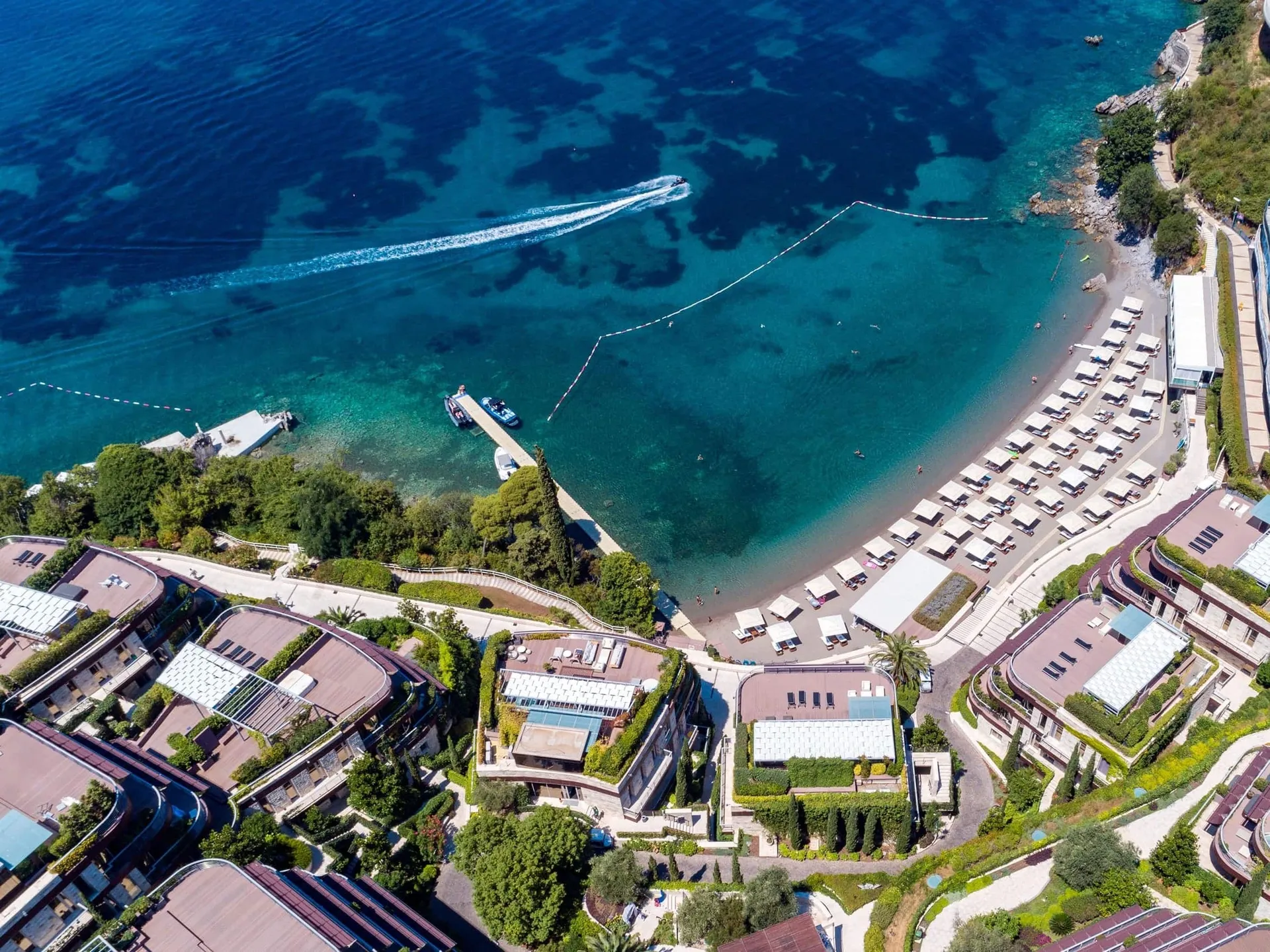 Luftaufnahme eines exklusiven Wohnkomplexes in Budva, Montenegro, mit Privatstrand und Yachthafen.