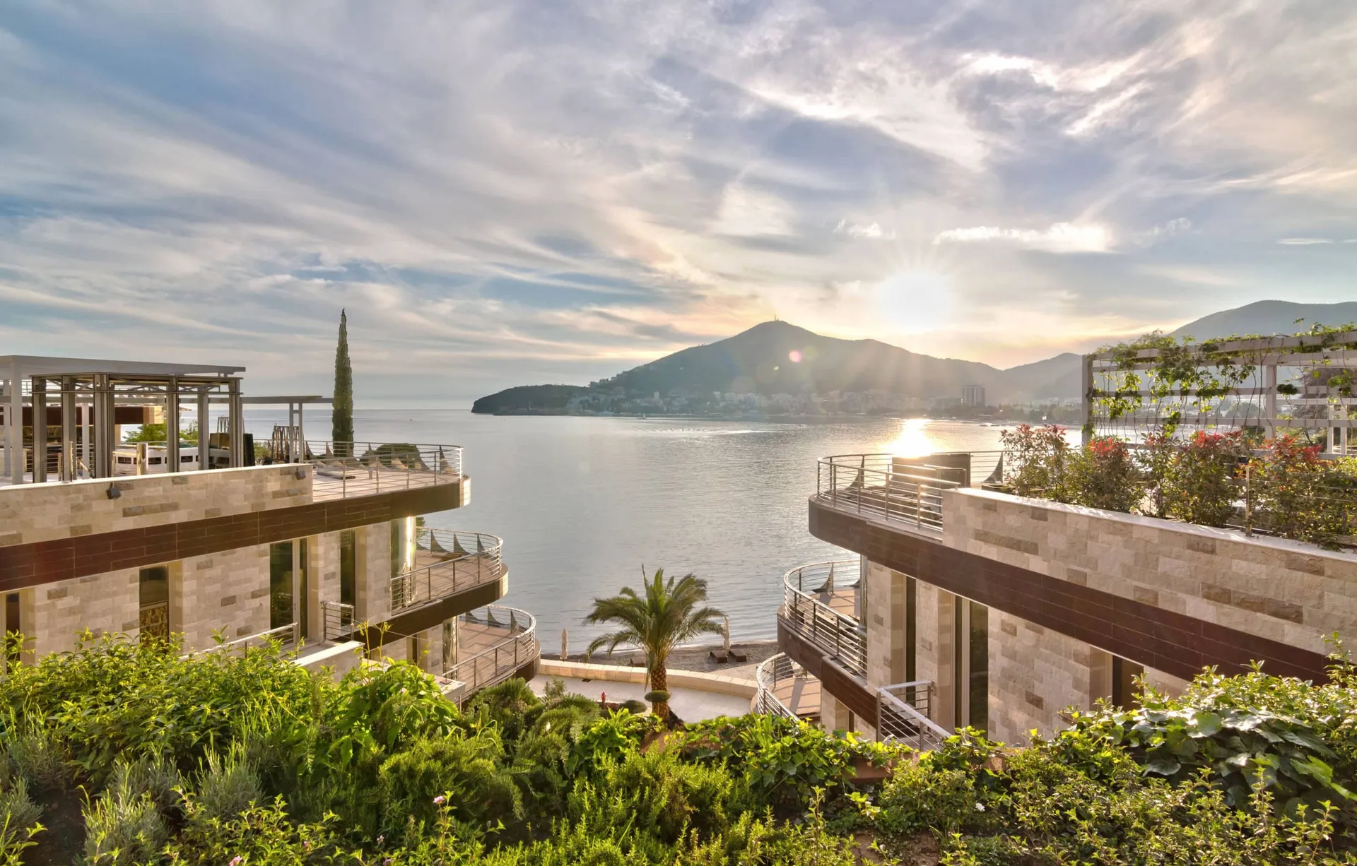 Moderne Villen mit Terrassen am Meer in Budva, Montenegro: Blick auf den Sonnenuntergang, die Berge und das gepflegte Gelände der Anlage.