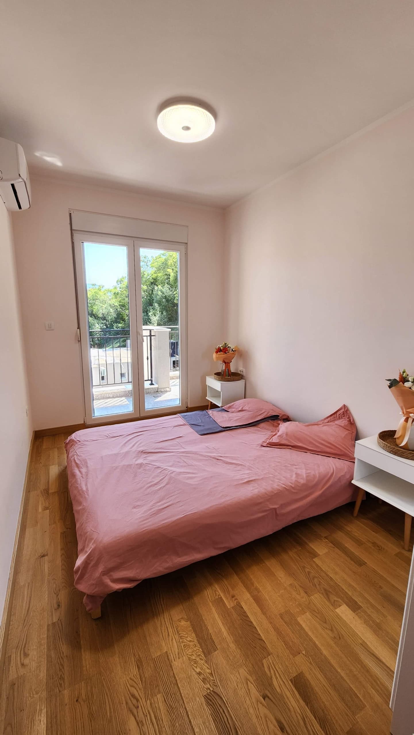 Cozy bedroom with a double bed, parquet flooring, and balcony access in an apartment in Budva, Montenegro.