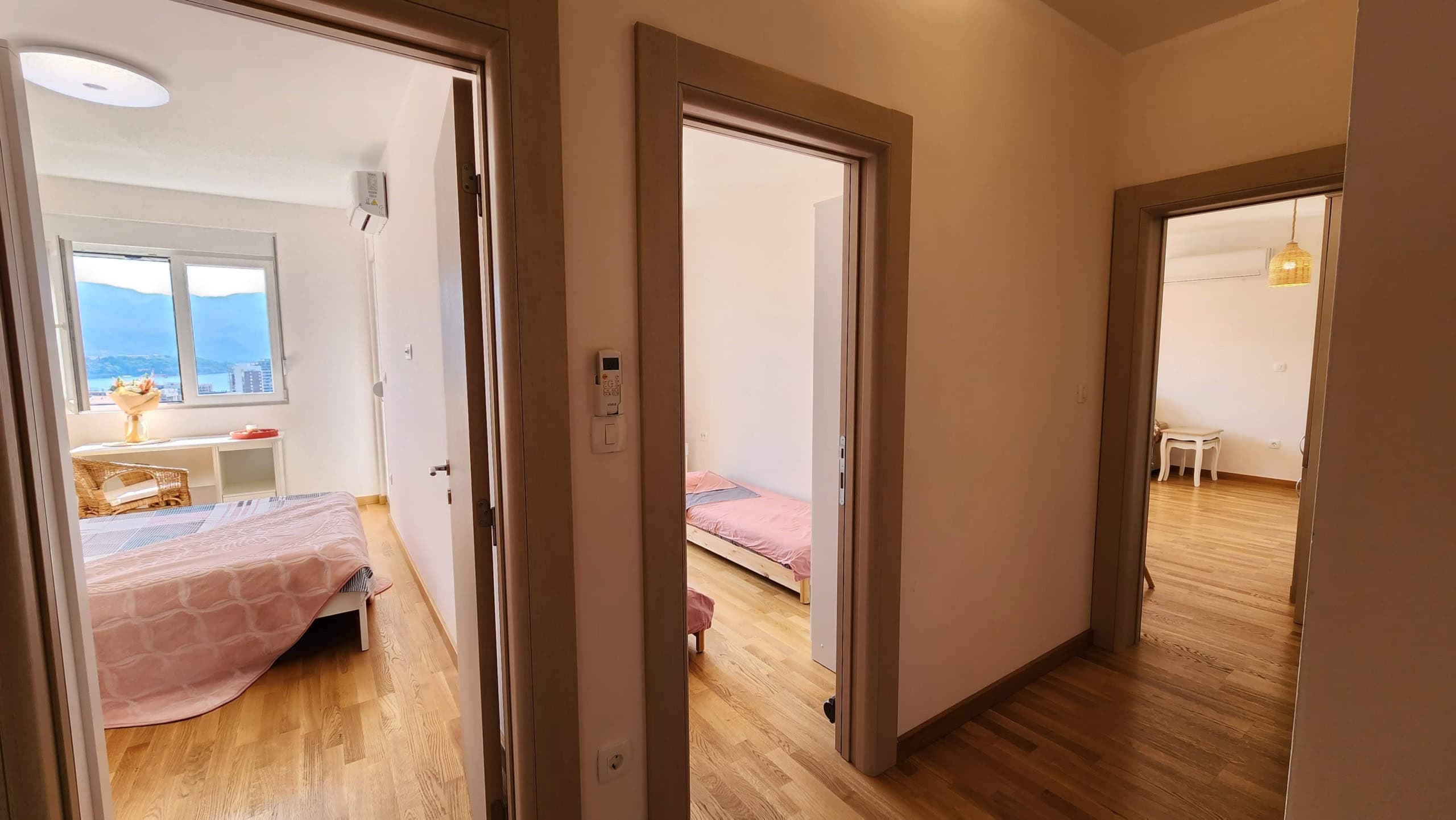 Interior of an apartment in Budva, Montenegro: bright bedrooms with parquet flooring, furniture, and a sea view from the window.