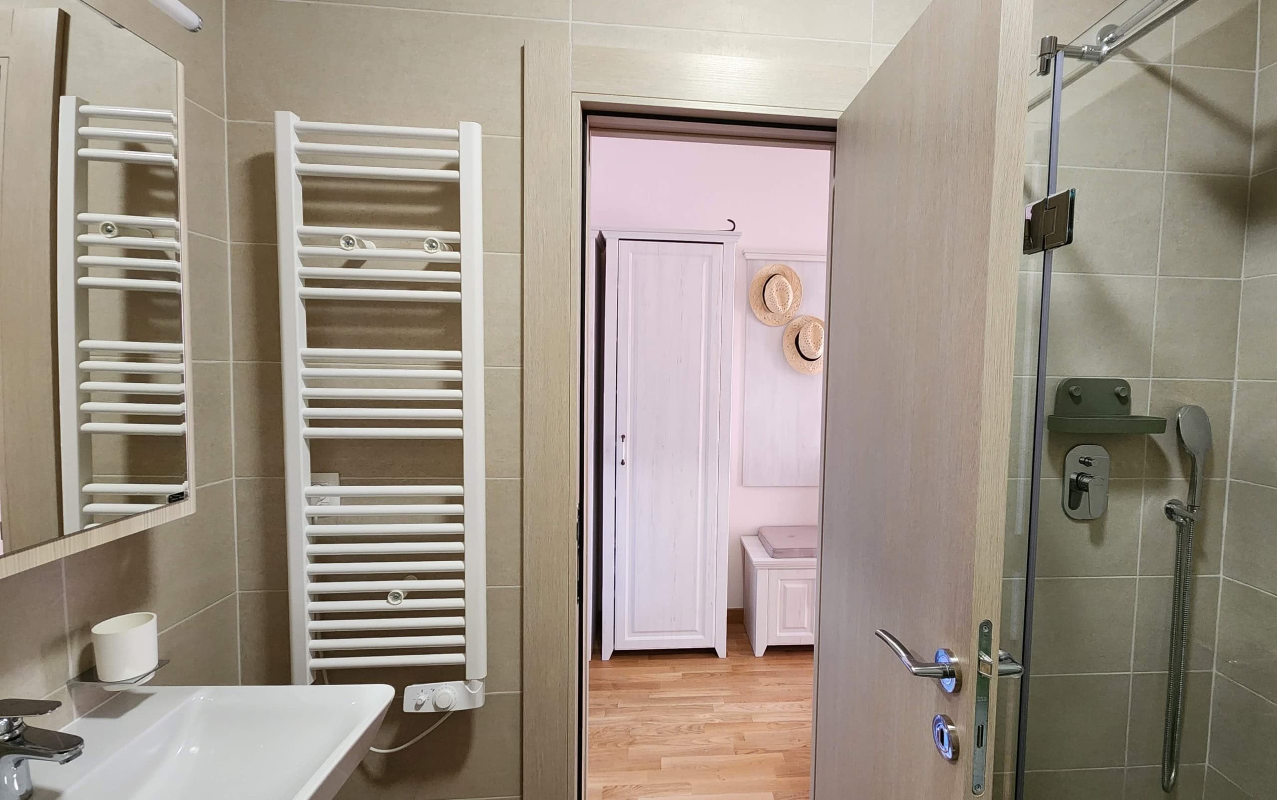 Modern bathroom with a walk-in shower in a Budva apartment, Montenegro, view into a bright bedroom.