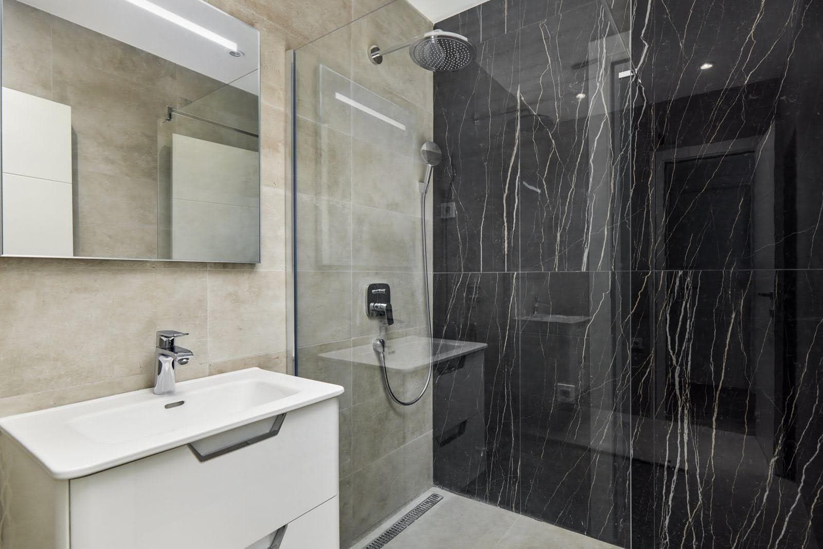 Karadağ, Prčanj’deki villada duş kabinli ve siyah mermer kaplamalı modern banyo.