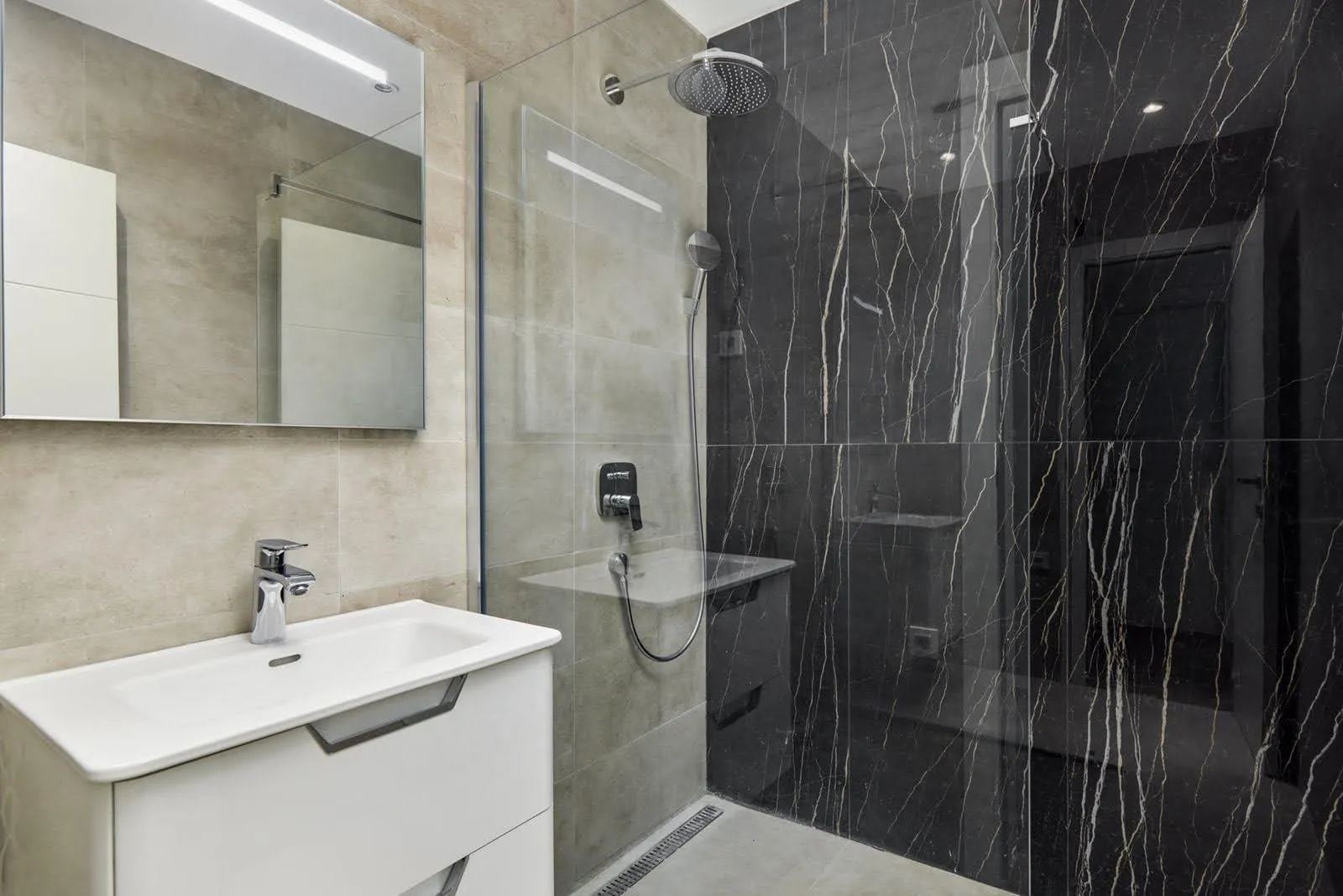 Karadağ, Prčanj’deki villada duş kabinli ve siyah mermer kaplamalı modern banyo.