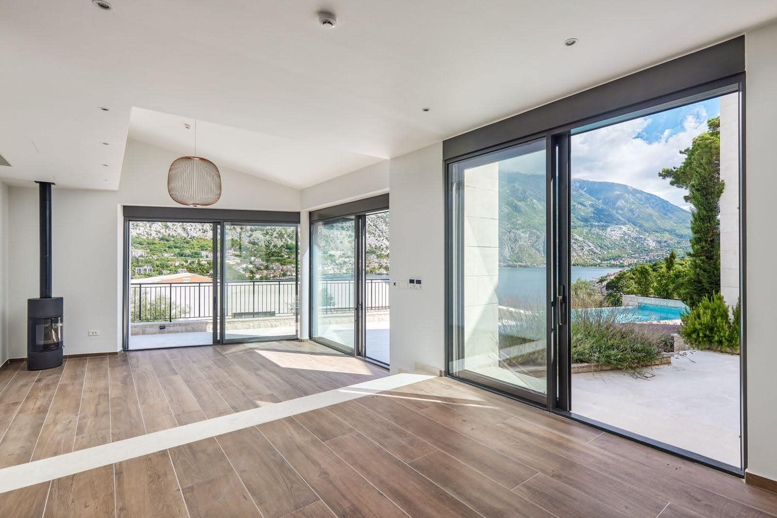 Deniz ve dağ manzaralı, panoramik pencereli ve şömineli oturma odası, villa, Prčanj, Karadağ. Modern iç mekan.