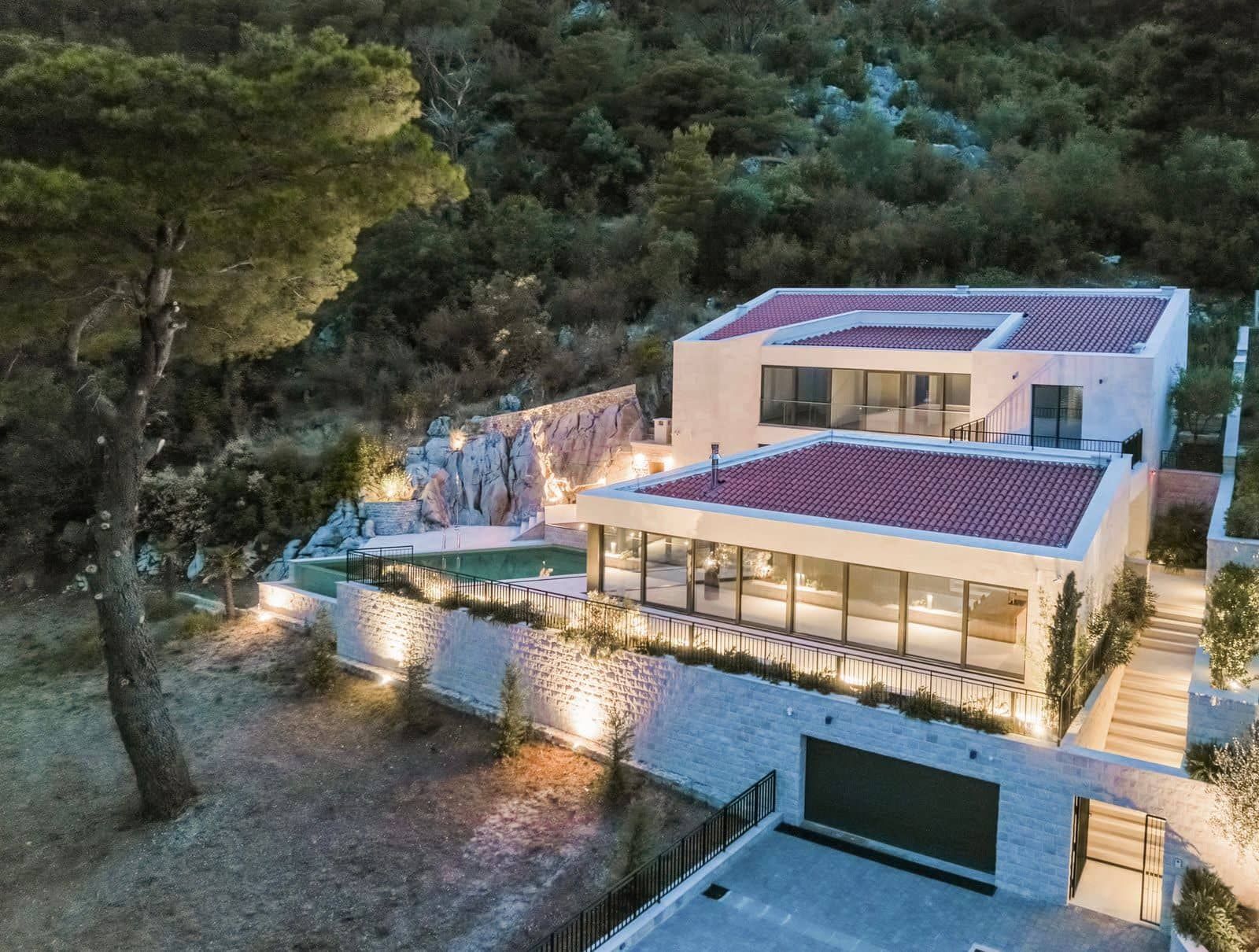 Karadağ, Prčanj’de havuzlu ve panoramik pencereli modern villa: aydınlatmalı dış cephe ve teras görünümü.